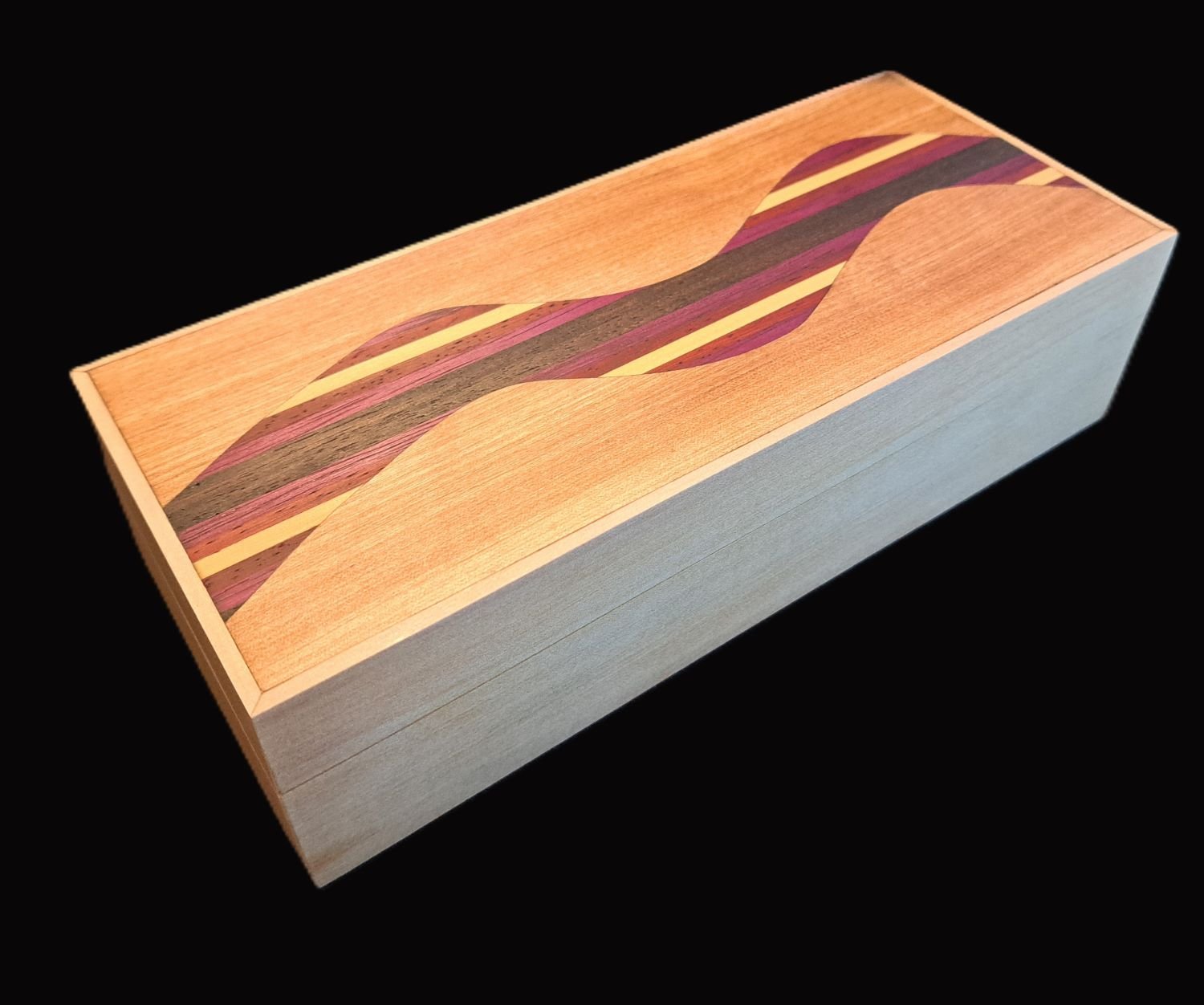 A wooden box with an artistic inlay design featuring wavy stripes in natural wood tones and purple, yellow, and red accents.