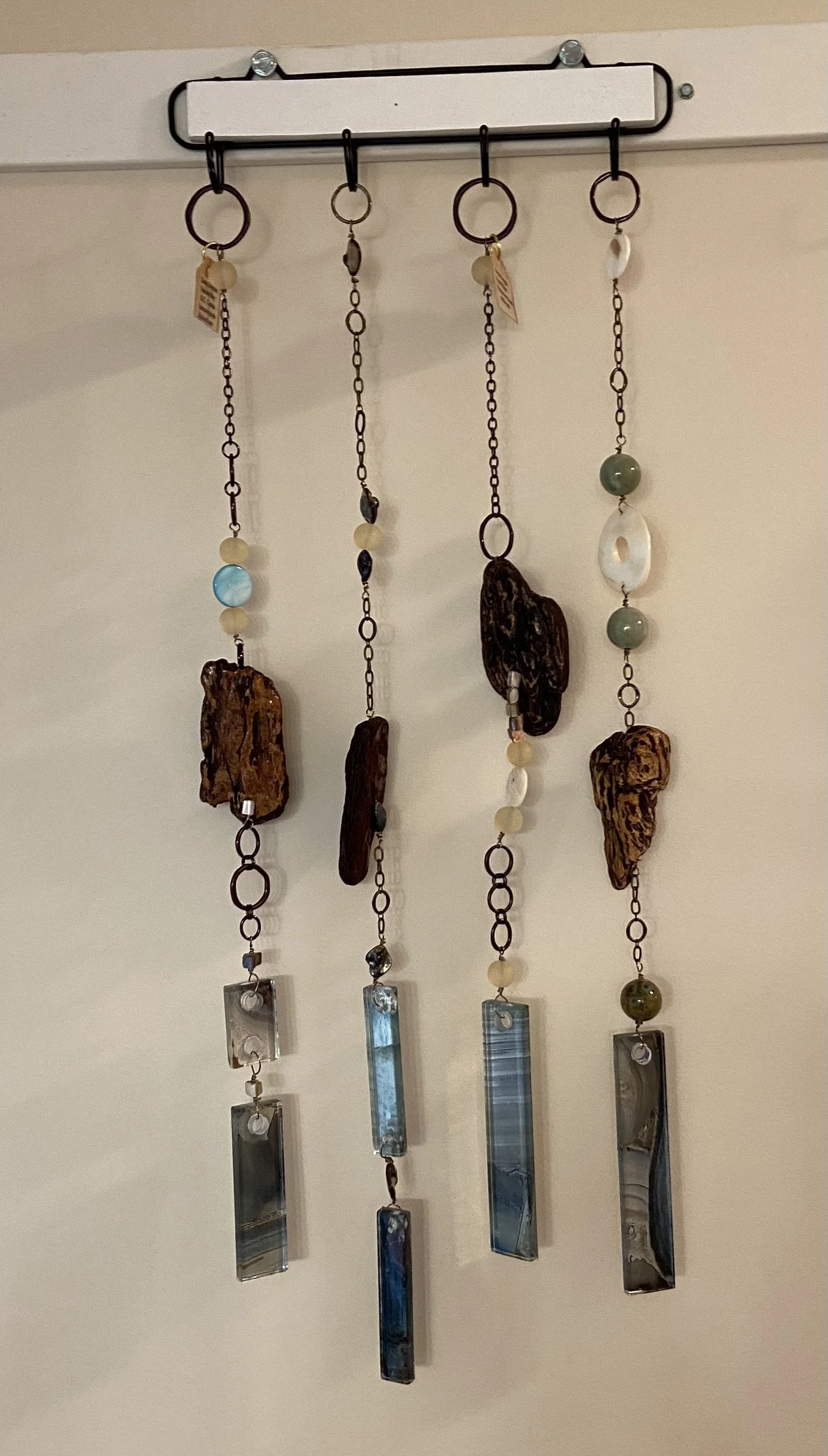 Decorative hanging wind chimes made of wood, beads, and glass with metal chains.