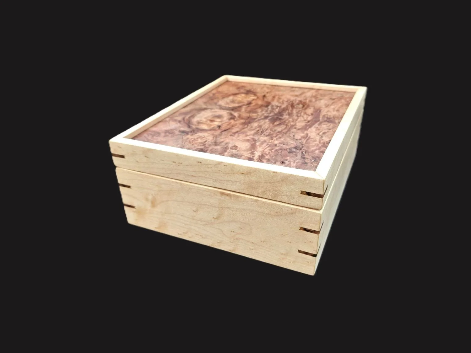 A wooden box with a marbled top, light wood construction, dovetail joinery on the sides, and a contrasting dark marbled surface on top, set against a black background.
