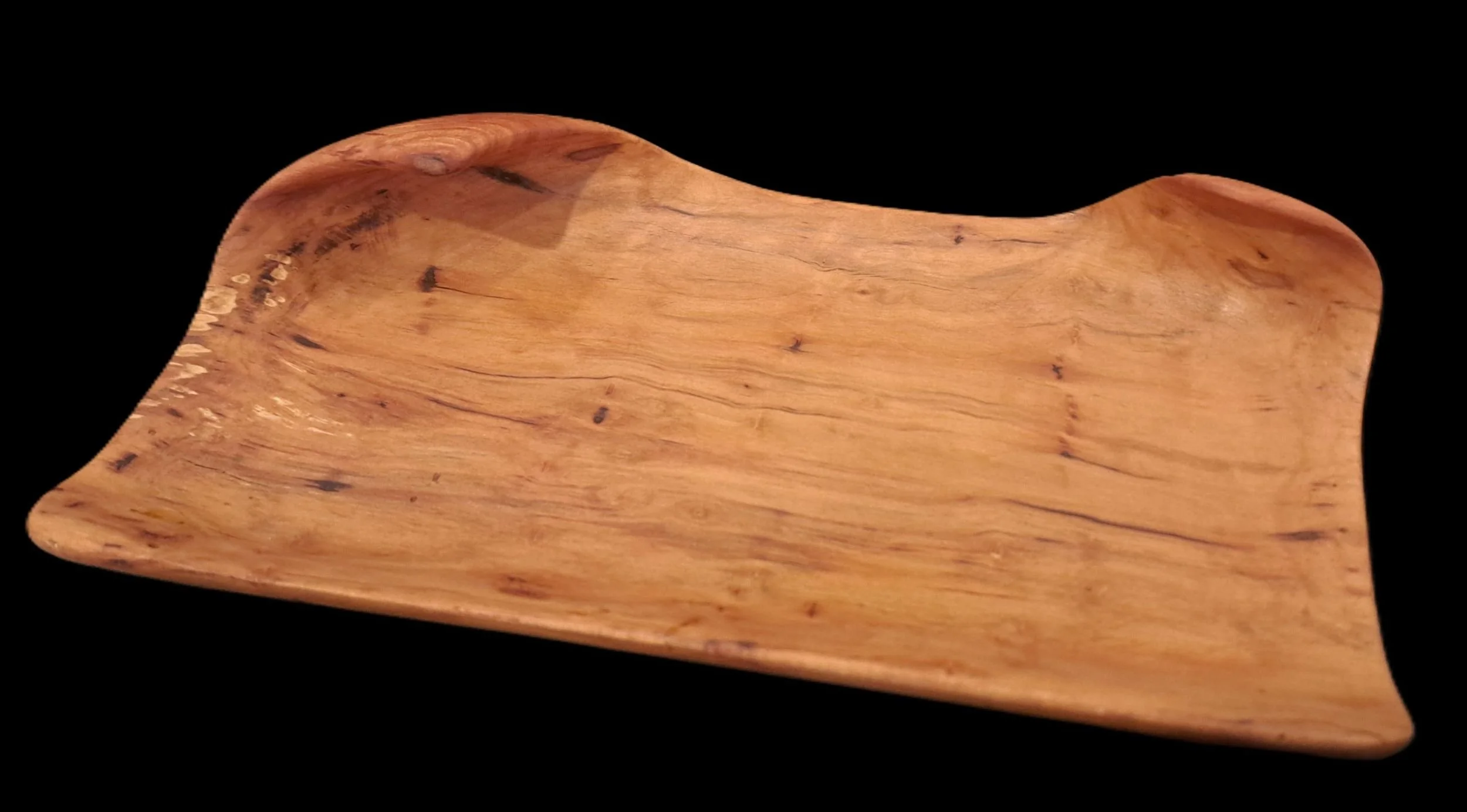 Wooden soap dish with a curved, smooth shape on a black background.