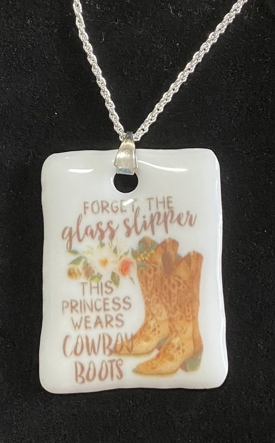 A necklace with a rectangular pendant featuring a quote and an illustration. The quote reads, "Forget the glass slipper, this princess wears cowboy boots," alongside an image of cowgirl boots and flowers.