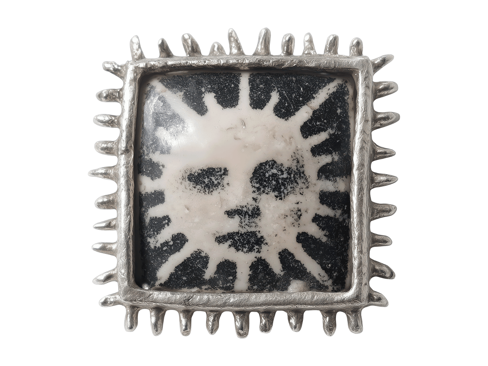 A decorative square metal frame with protruding spikes on all sides surrounds a face-shaped design in black and white, resembling a stylized skull or mask.