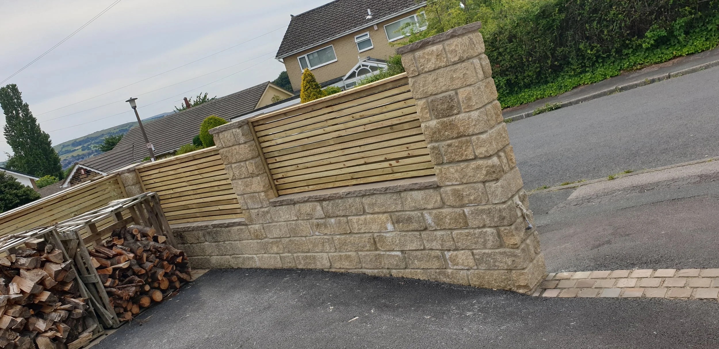 Stone wall with wooden slats near road