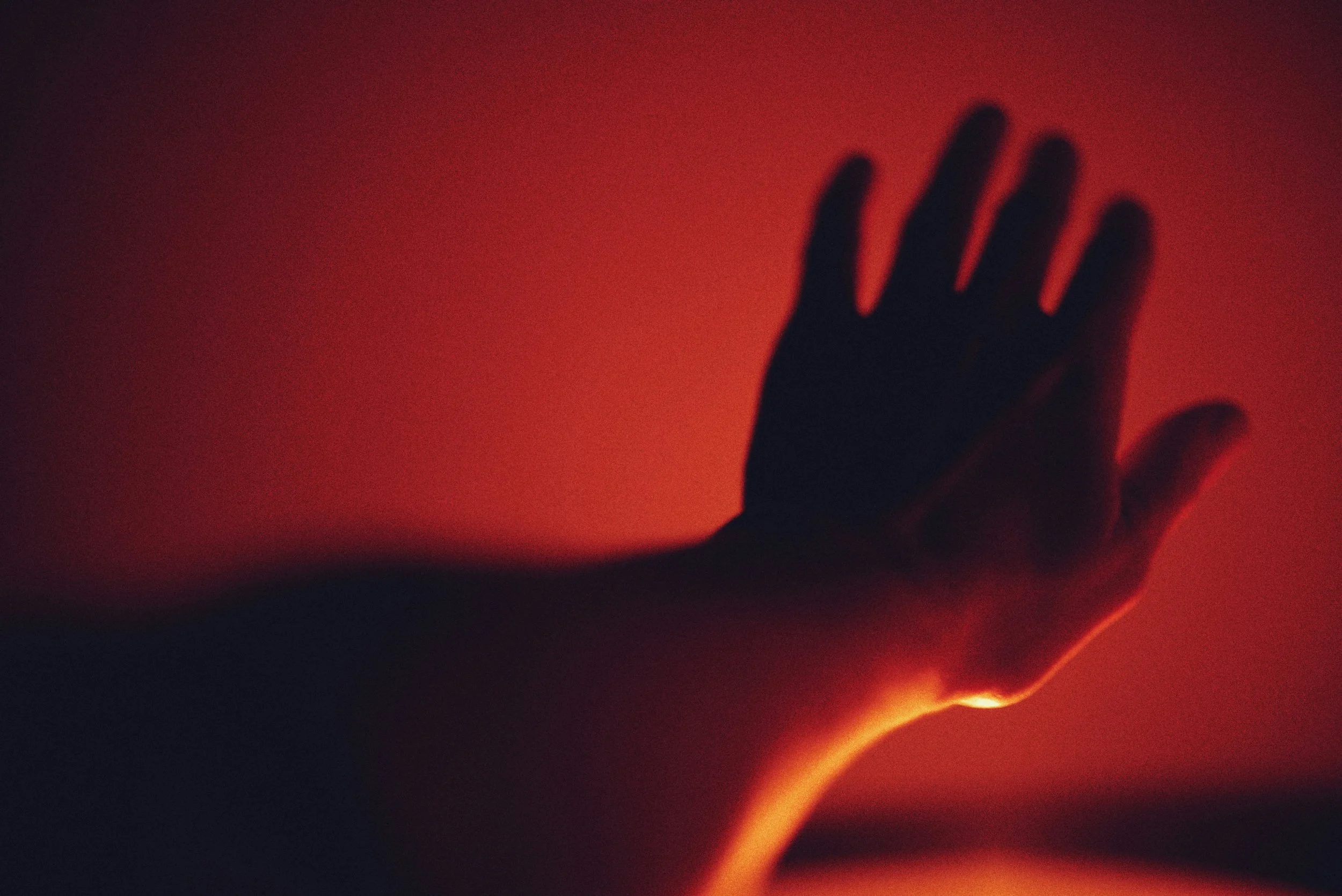 A human hand reaches toward a warm beam of light emerging from darkness, symbolizing grace, encounter, transmission, and the living experience of a charism.