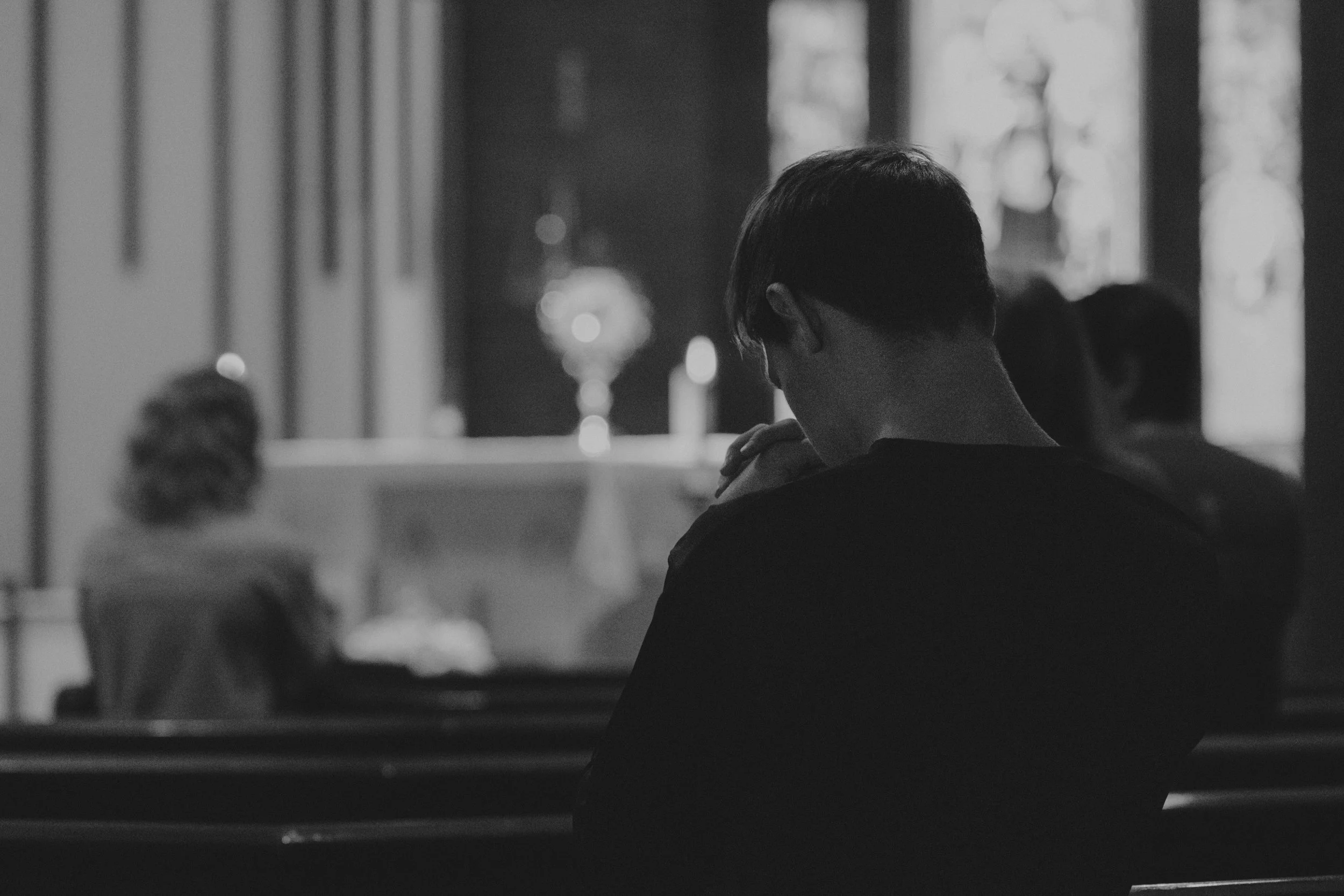 Black and white photo of a person praying inside a church, symbolizing ecclesial discernment, humility, and spiritual governance.