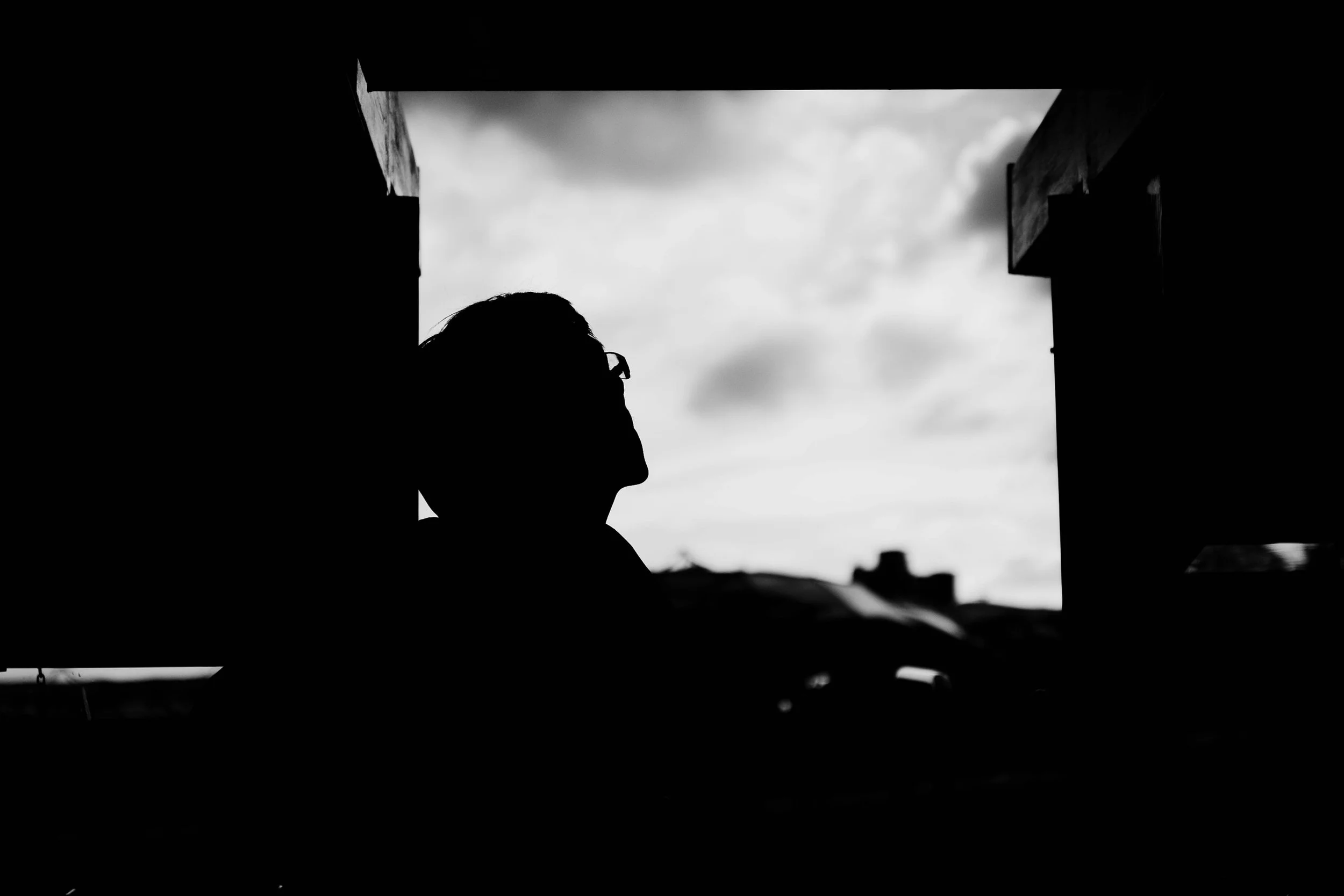 Black-and-white silhouette of a person looking toward the open sky, evoking longing, recognition and presence.