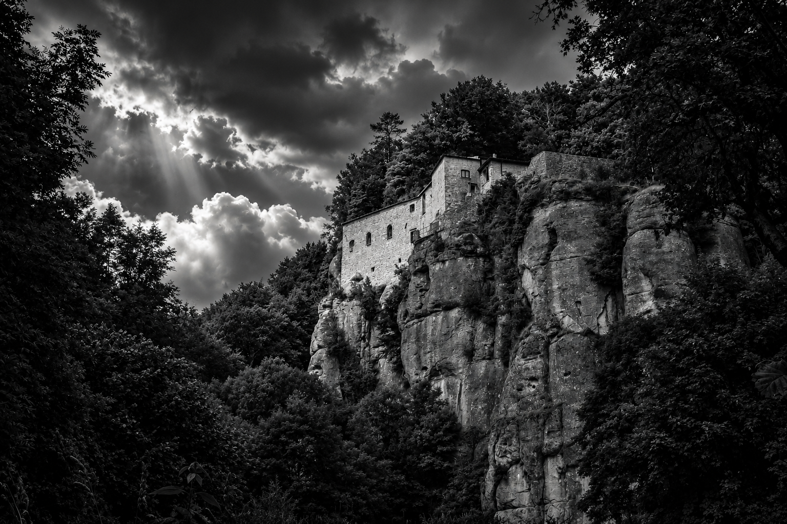 Stone monastery perched on a rocky cliff above a forest under dramatic black-and-white clouds and rays of light.