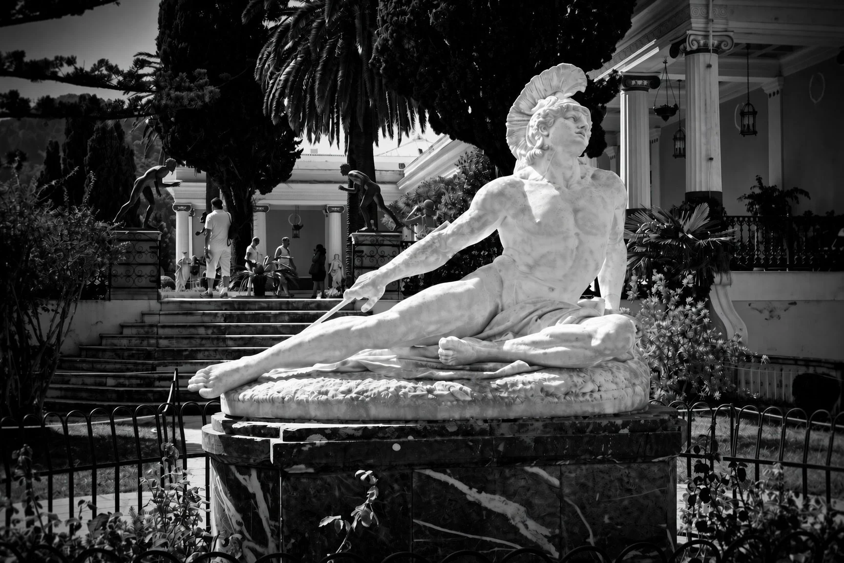 Black-and-white photograph of the reclining Achilles statue at Achilleion Palace, Corfu, embodying Homeric force and human vulnerability.