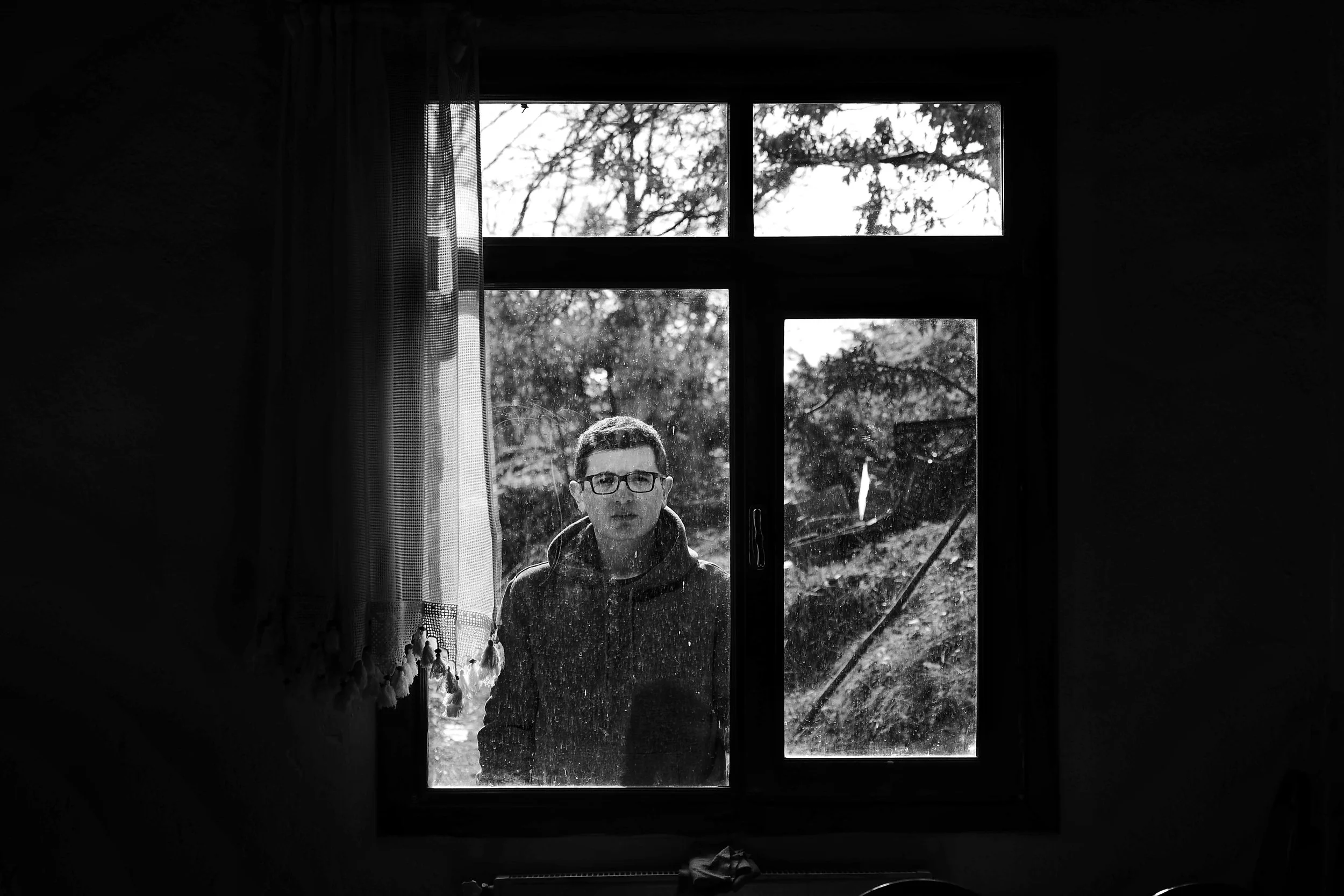 Elderly man keeping watch at a window in black and white, evoking the watchman for the house of Israel