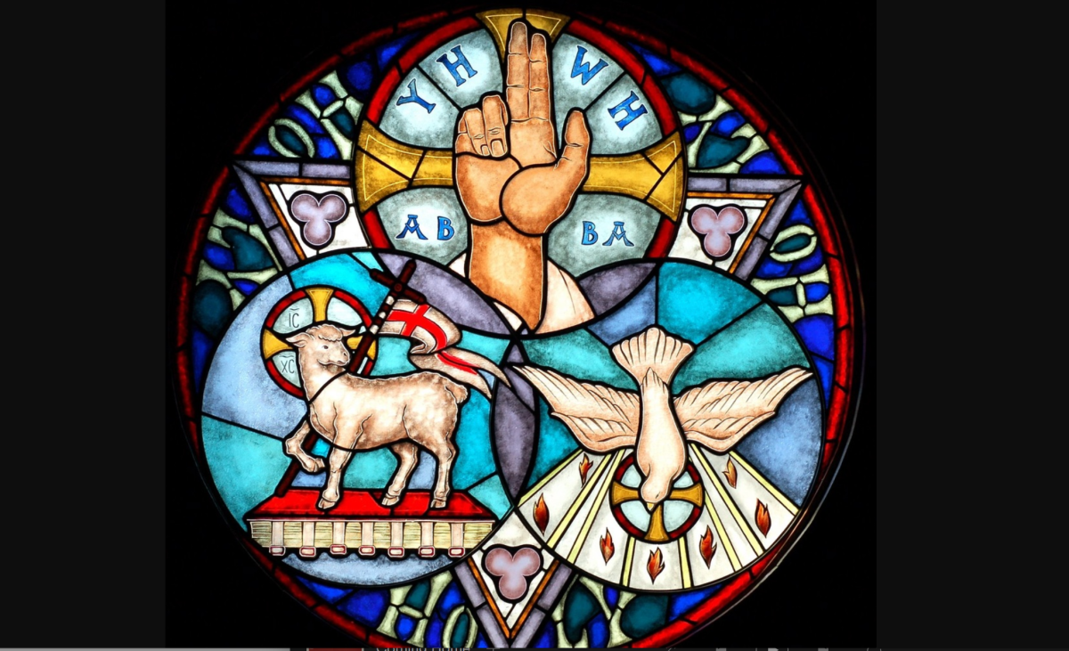 Stained-glass window of the Holy Trinity with the hand of God, the Lamb of Christ, and the dove of the Holy Spirit.