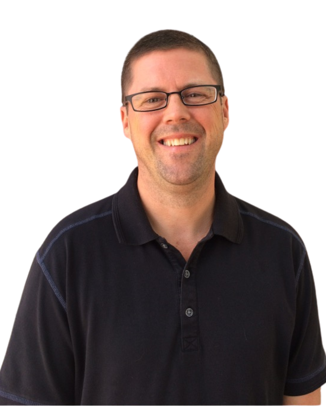A smiling man wearing glasses and a black polo shirt standing outdoors near a building with large windows.