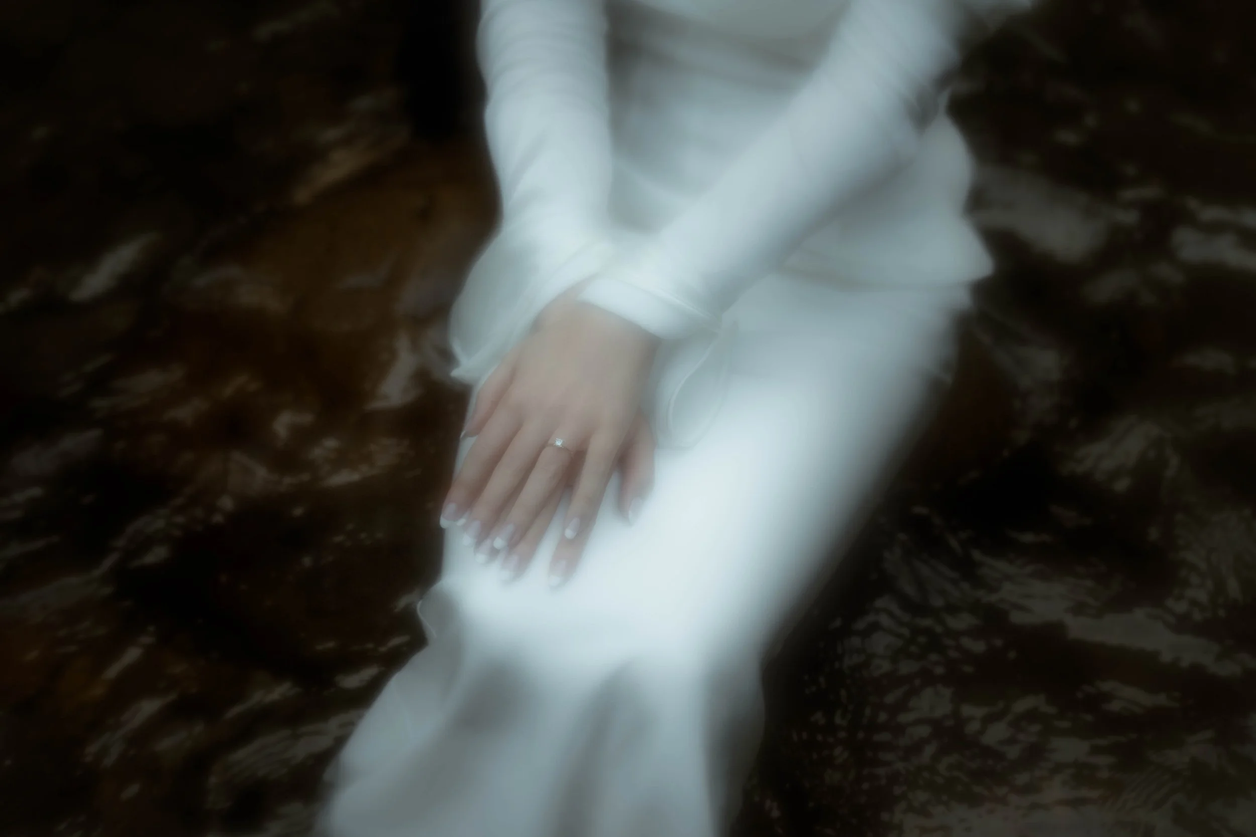 Une personne en vêtements blancs tenant la main d'une autre personne dans un environnement sombre et marbré.
