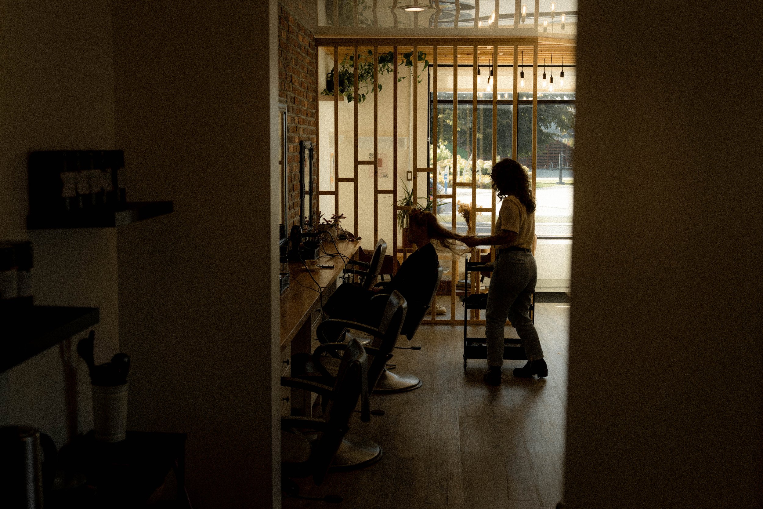 Une femme coiffant une autre femme dans un salon avec une grande fen