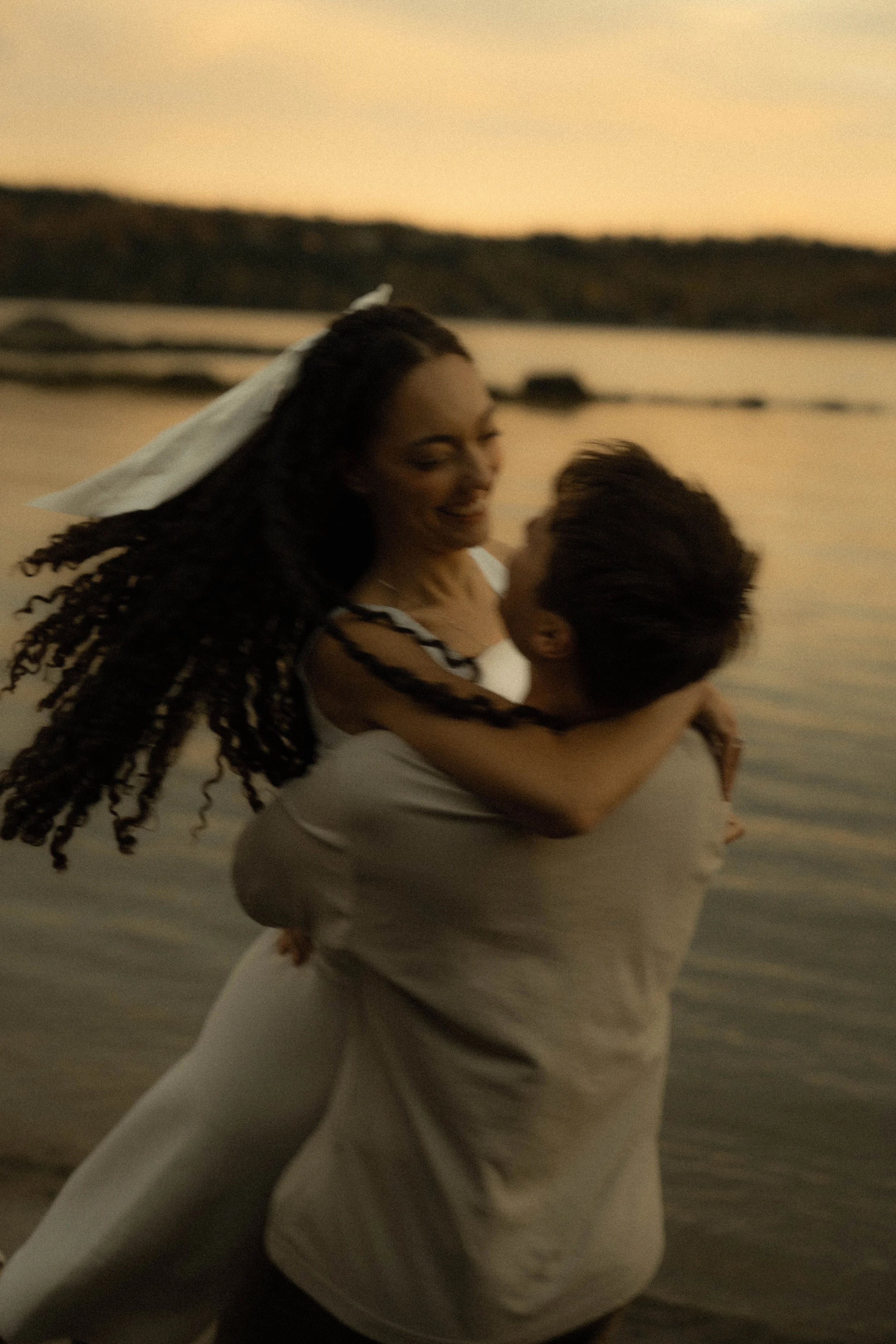 Une femme et un enfant souriant, emportés par la mer lors du coucher du soleil.