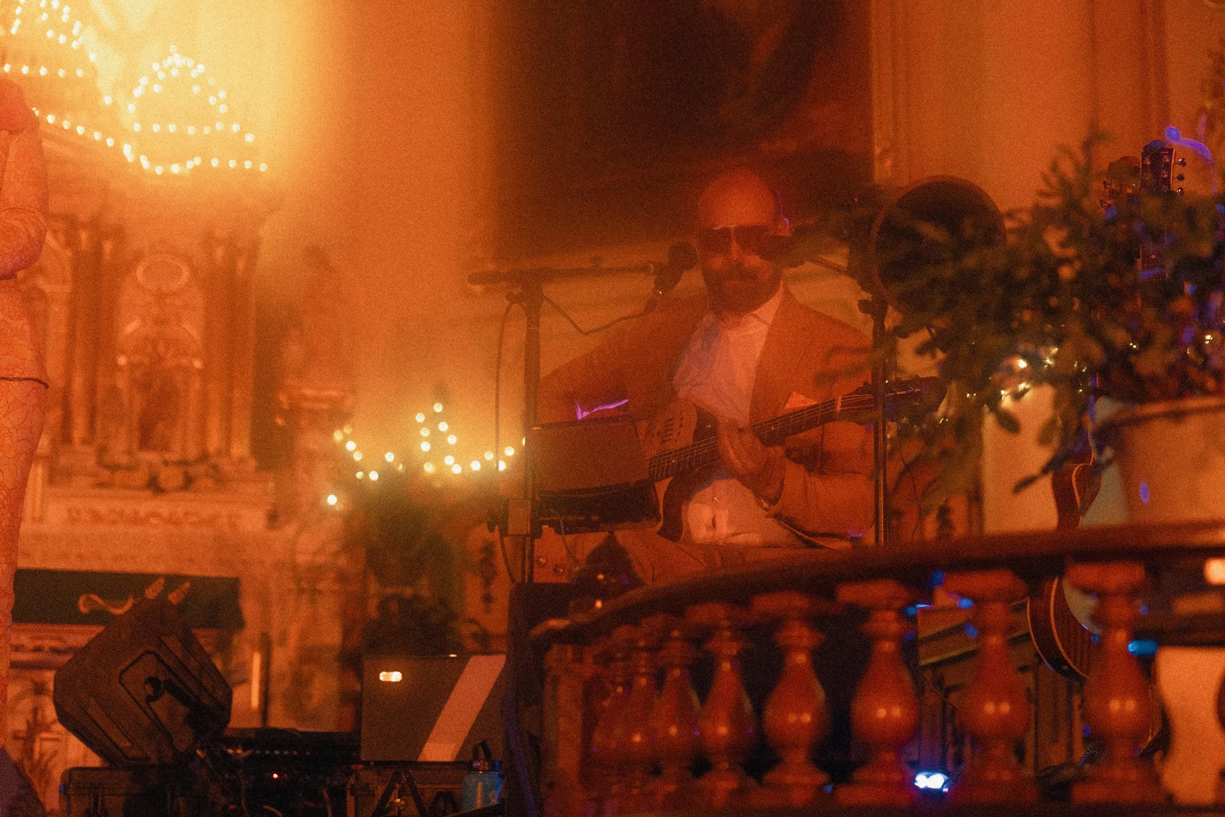Musicien avec guitare en pelure dans une église, éclairée par des lumières chaudes, décorations de Noël