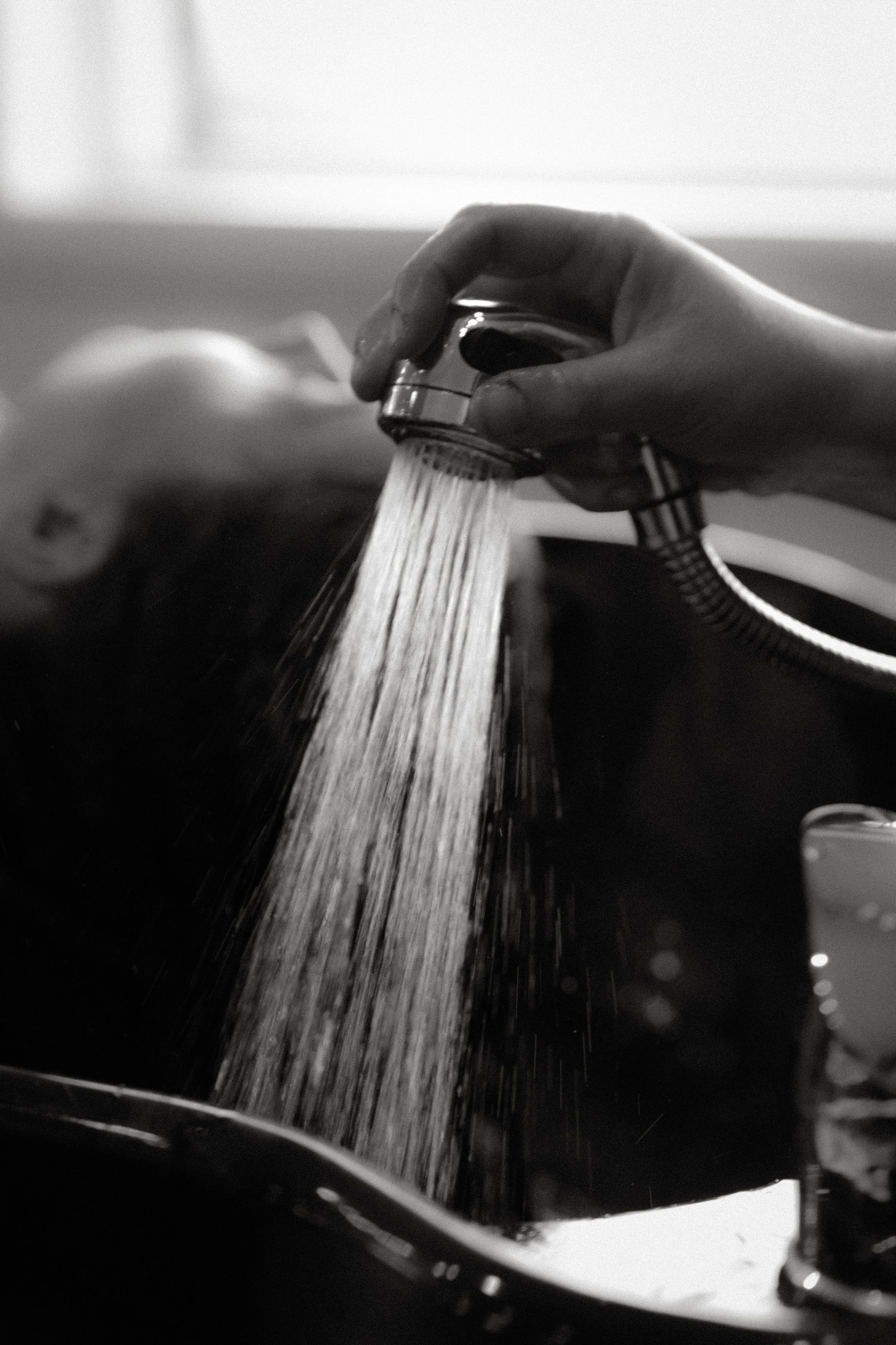 Mains tenant une pommeau de douche, aspergeant de l'eau. Vue en gros plan.