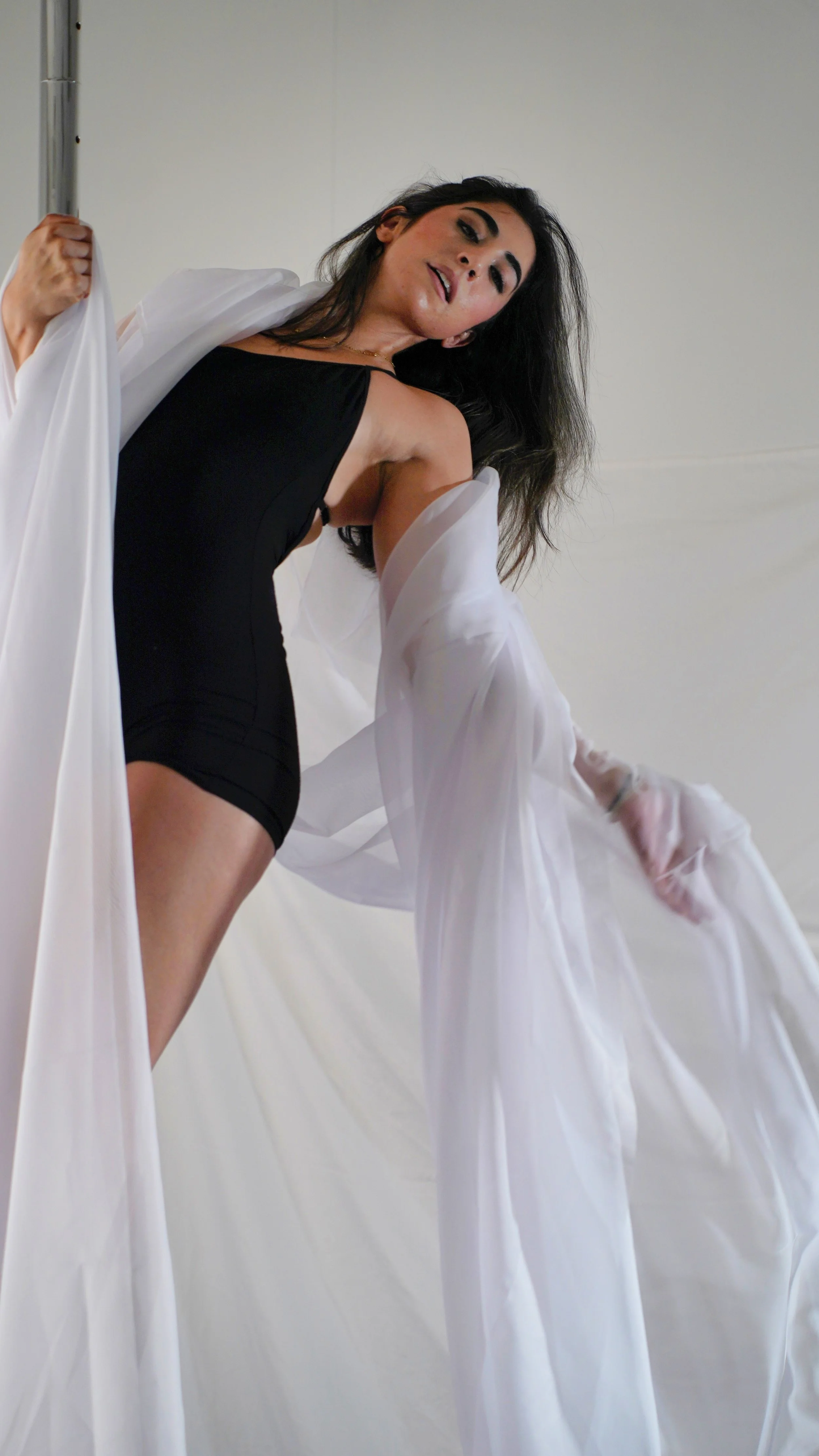 Woman draped in white silk hanging from a pole