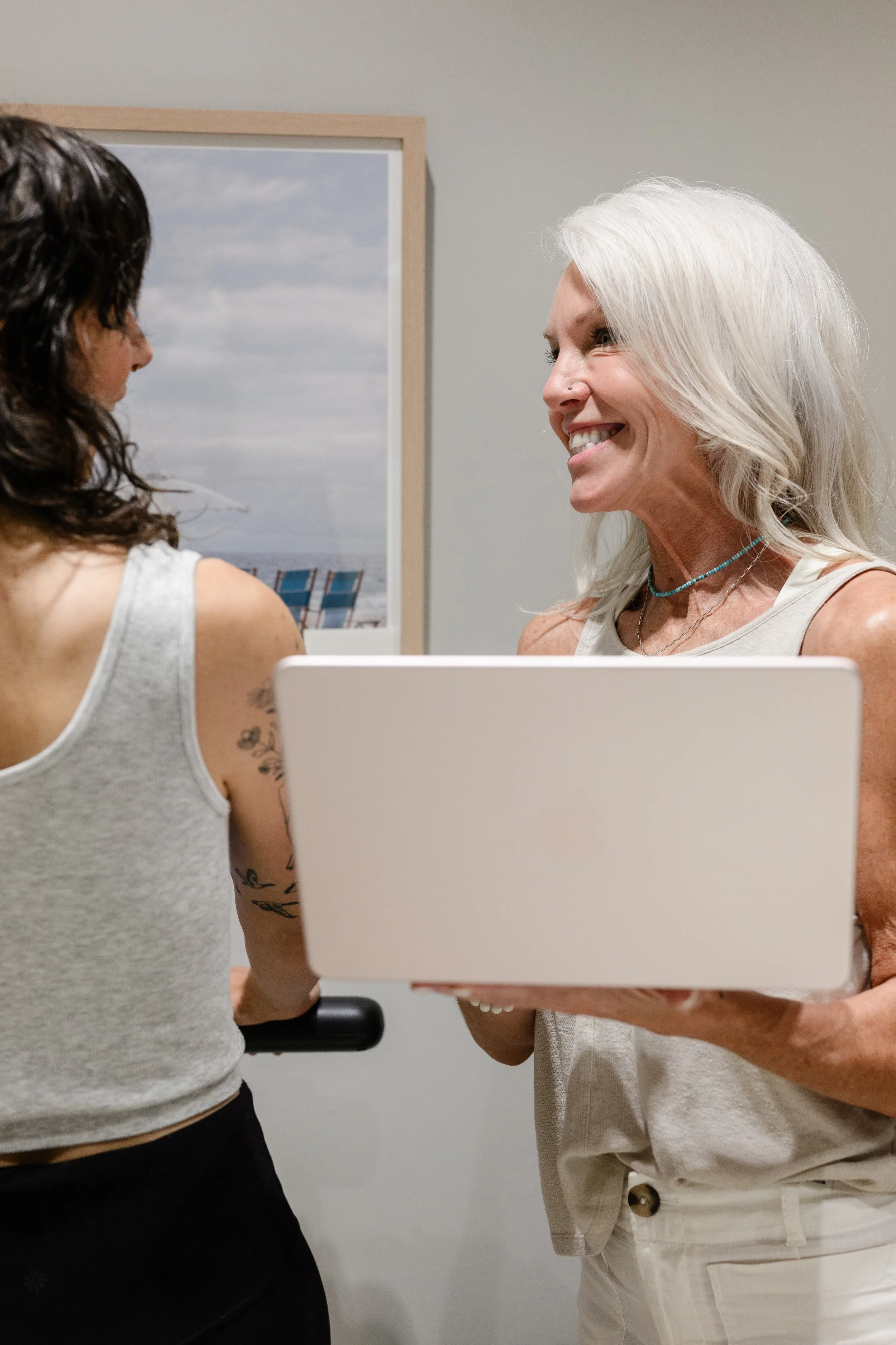 Two women standing face to face, completing a SECA body composition scan to review muscle mass, body fat and help her reach her goals safely and effectively while on a GLP-1 like tirzepatide or semaglutide.