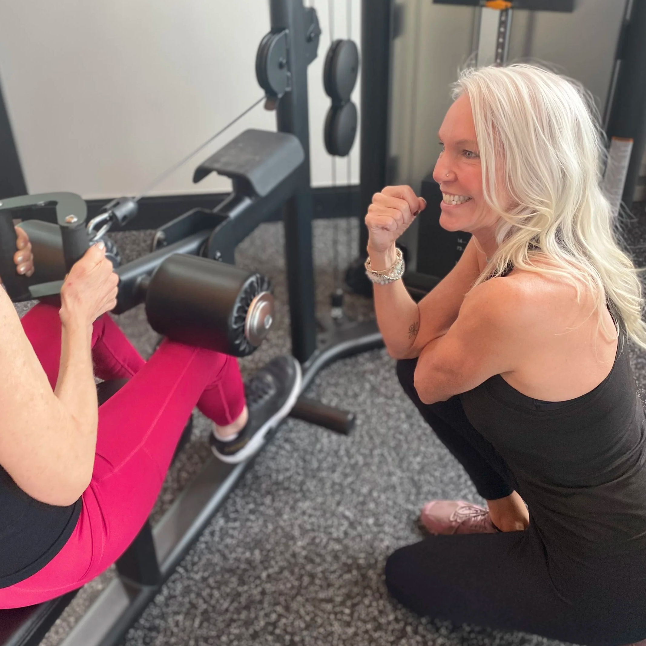 A smiling female healthcare professional in navy scrubs with a stethoscope around her neck, handing medication to a patient.