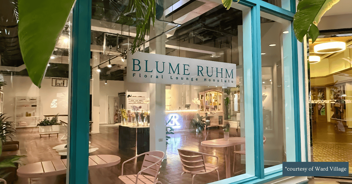 View inside a floral lounge named Blume Ruhm in Honolulu, with modern decor, plants, and seating area seen through large glass windows.