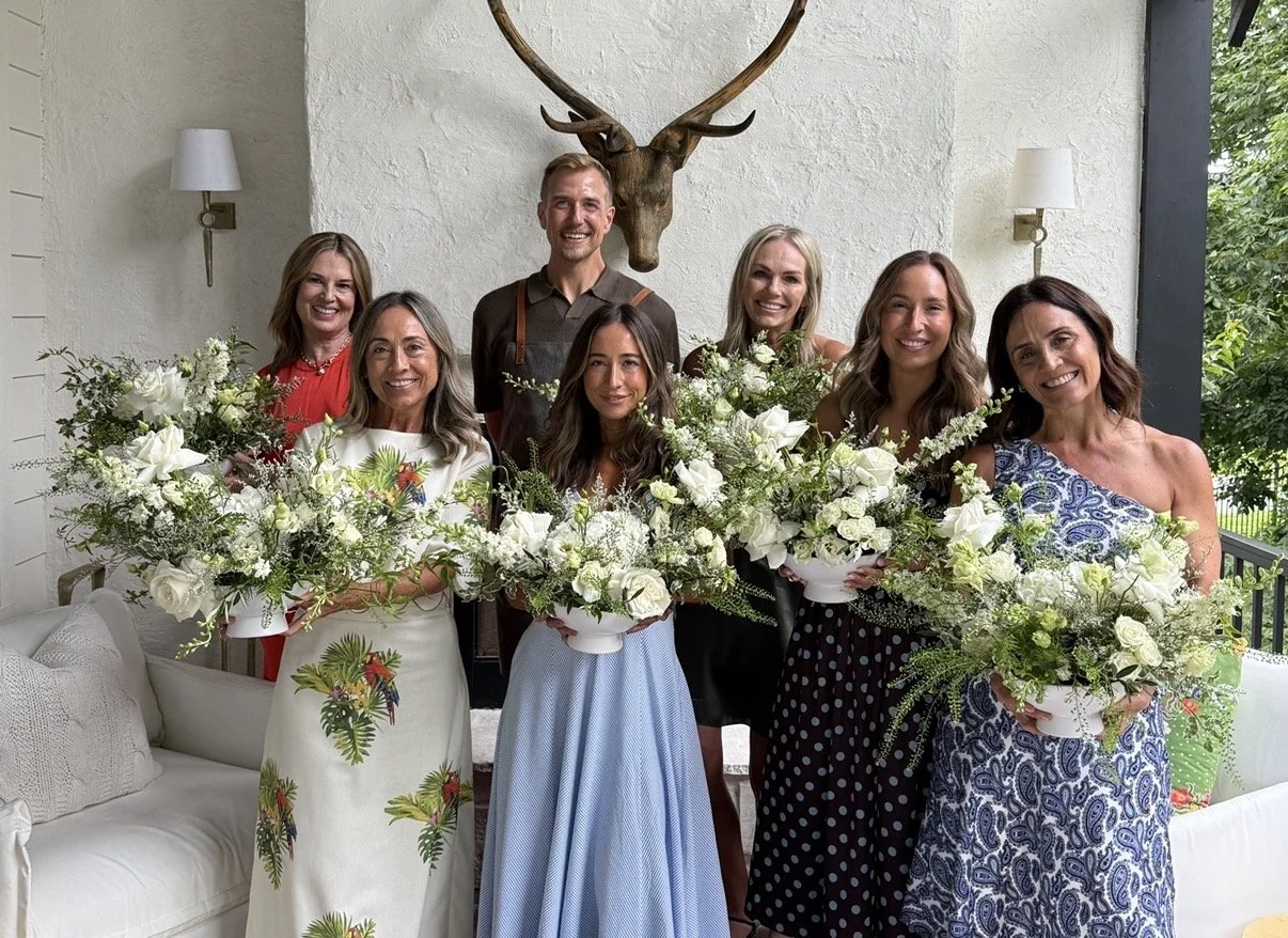 Guests holding finished floral arrangements at a Blossom Bar workshop