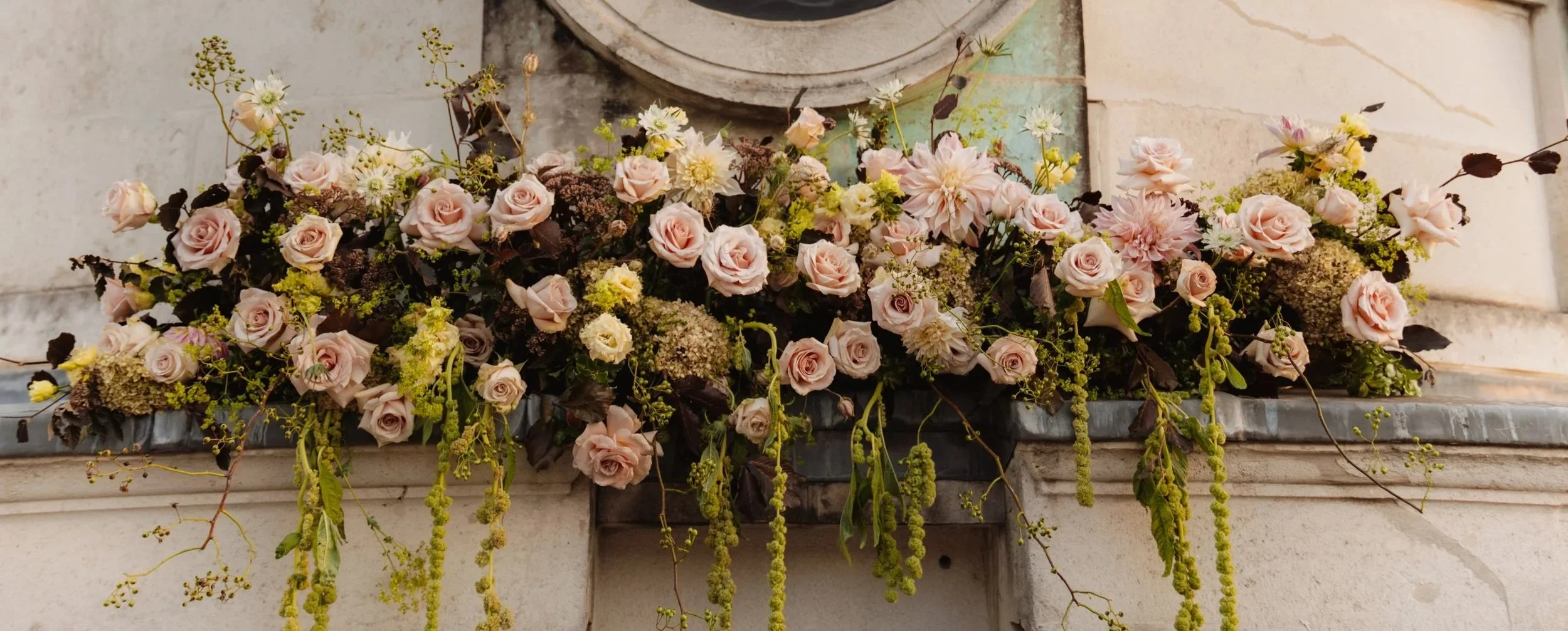Garden-inspired event floral installation with blush roses, white flowers and seasonal foliage.