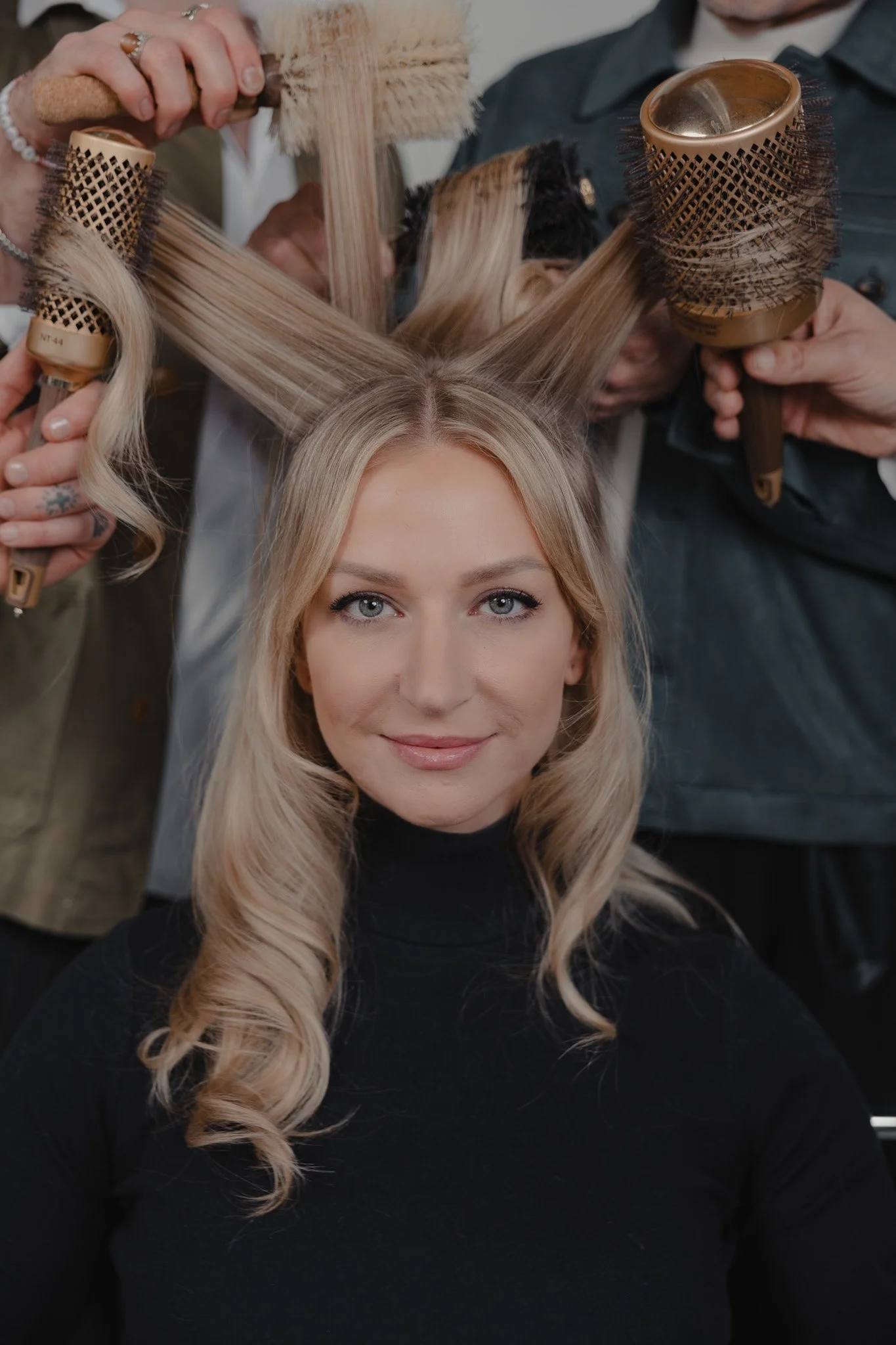 Blowout hairstyling in progress with round brushes on a blonde client