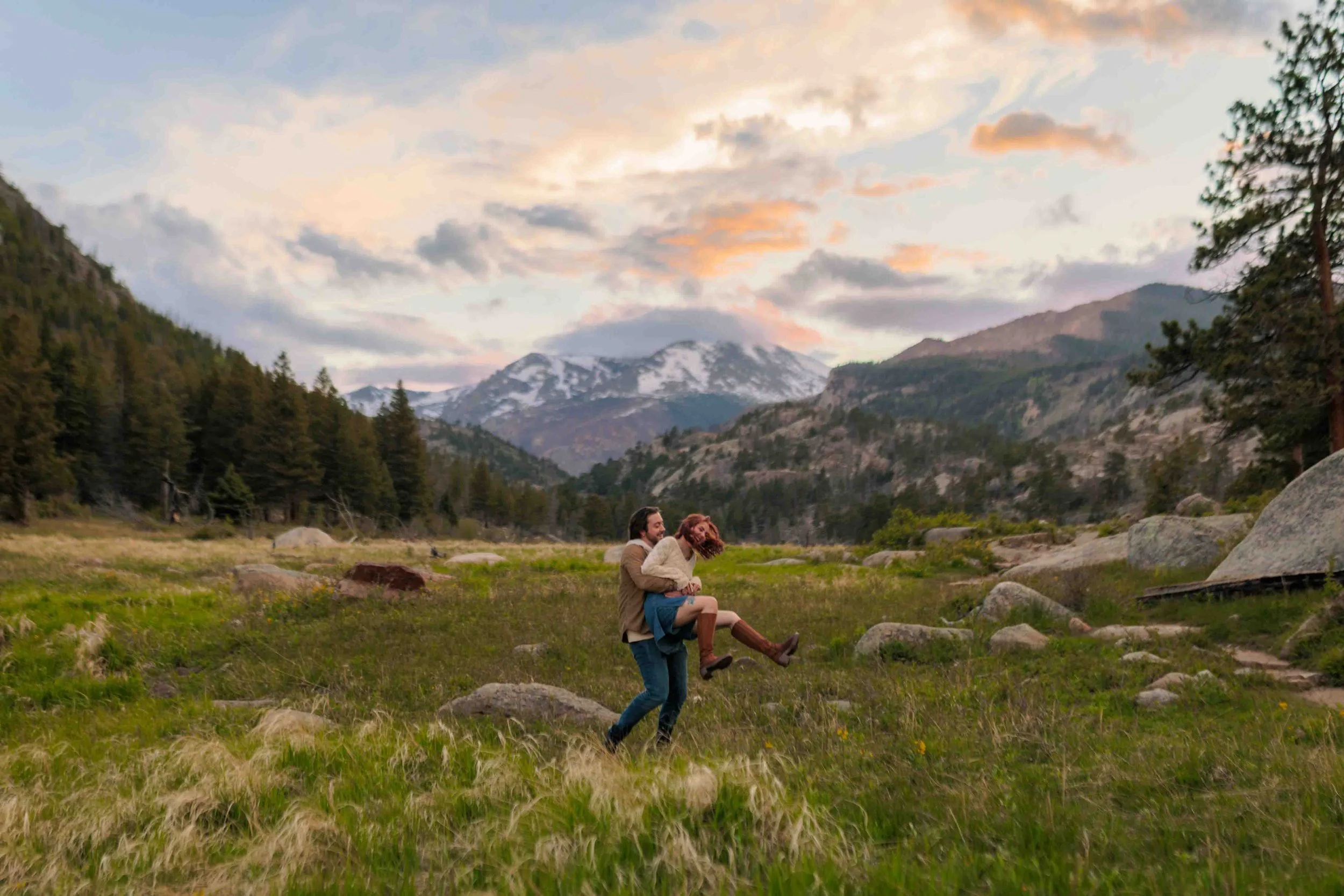 Colorado mountain couple session in a grassy field, with a man carrying his smiling partner during golden hour.