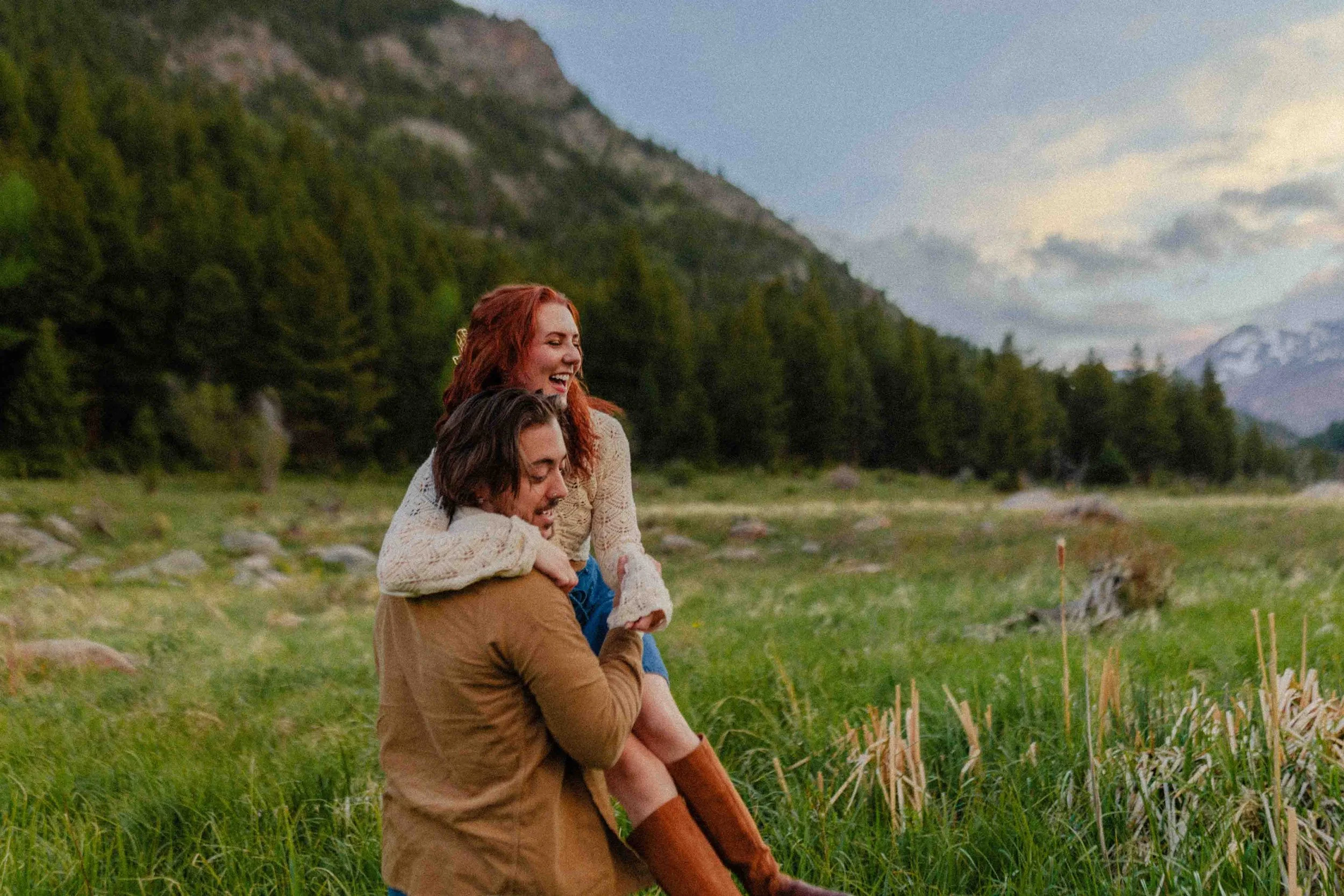 Colorado mountain couples session featuring a playful piggyback moment during a hike through alpine meadows and forest.