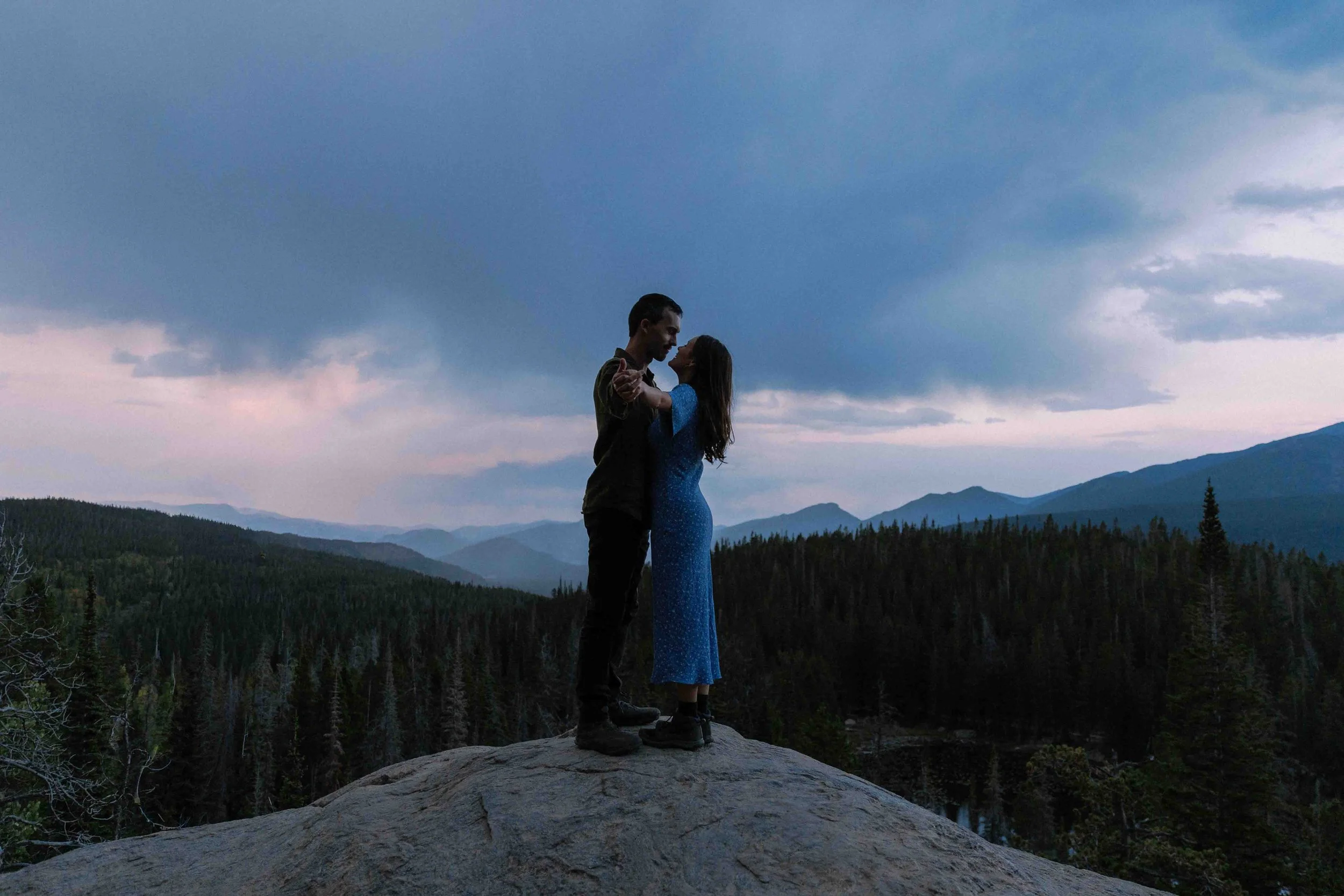 Estes Park engagement photo of a couple dancing on a rock at sunset in the Colorado mountains.