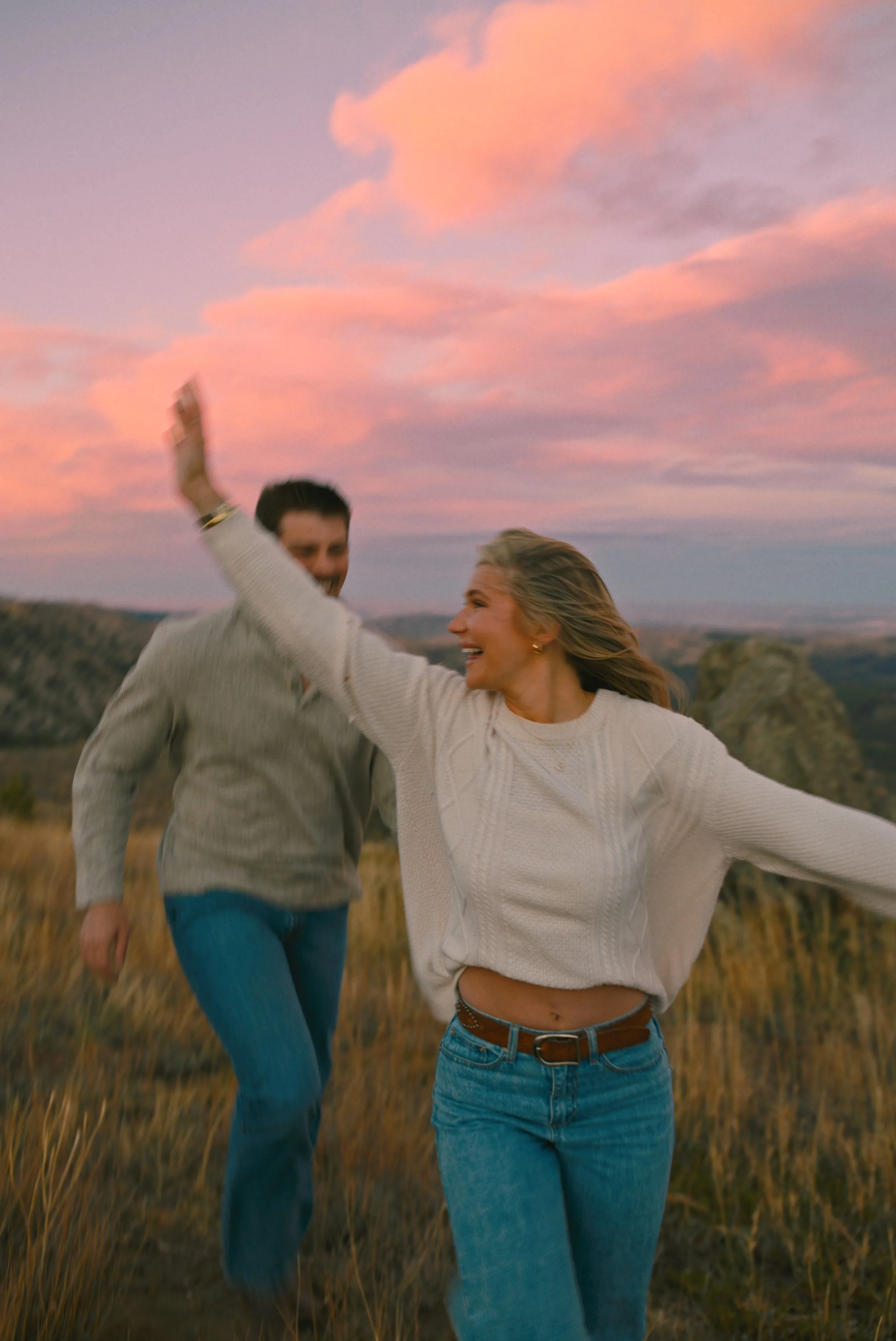Romantic Colorado mountain engagement session with candid moments in a grassy field.