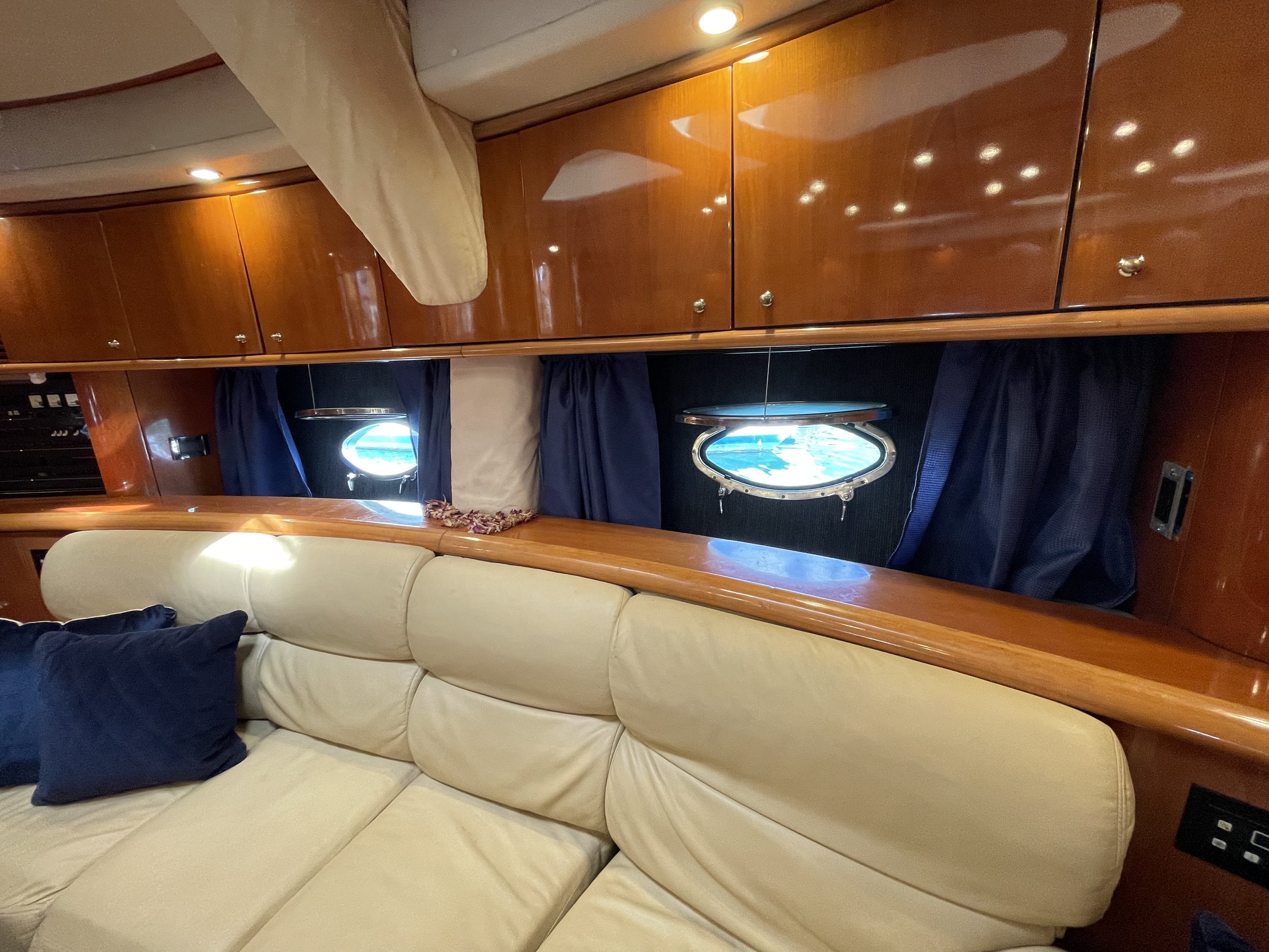 View of a cozy cabin interior with a curved wooden ceiling, built-in wooden cabinets, and a beige leather sofa with a dark pillow.
