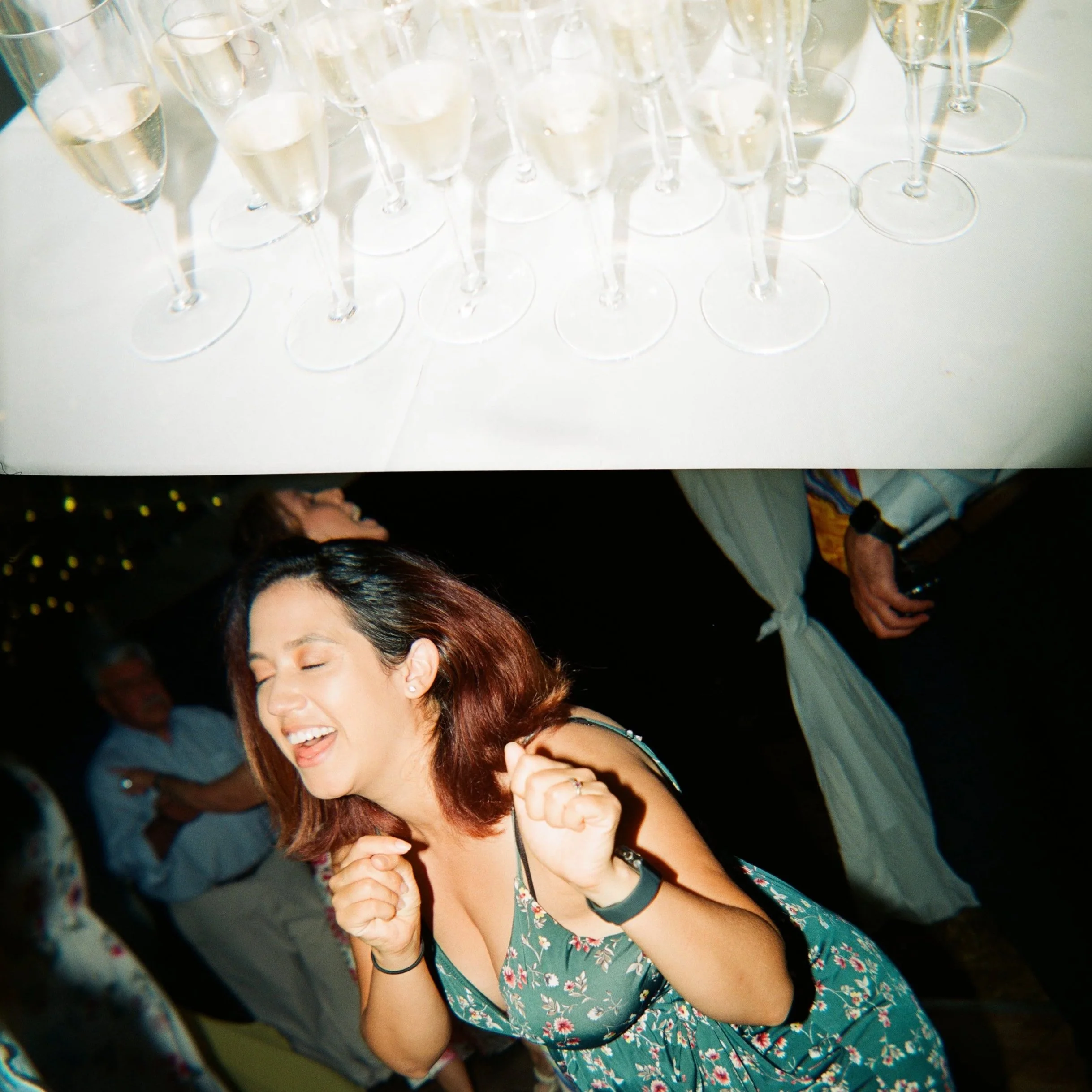 Glasses of champagne on a table and a woman dancing and enjoying herself at a celebration or party.