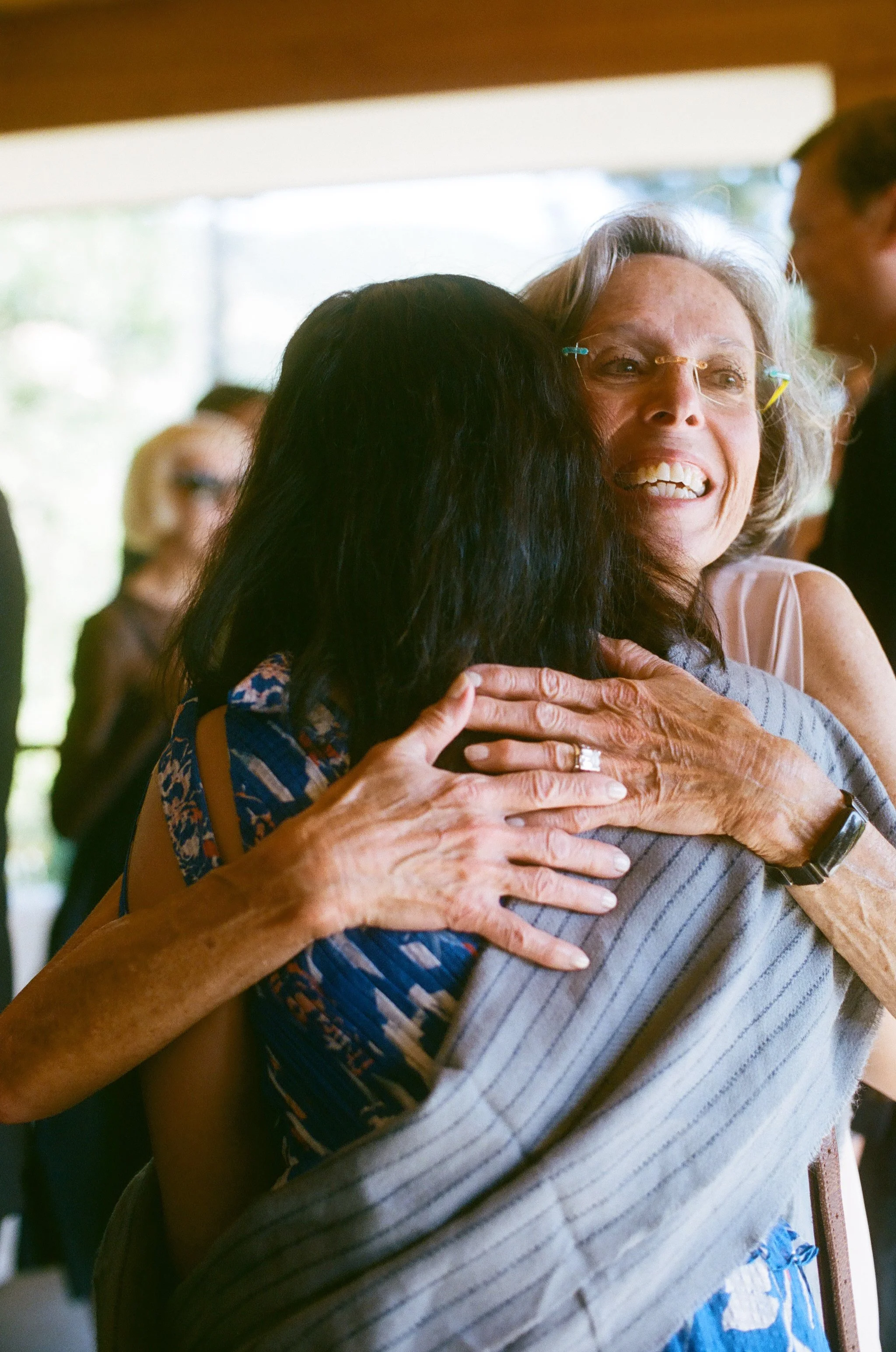Two women hugging at a social gathering, smiling warmly.