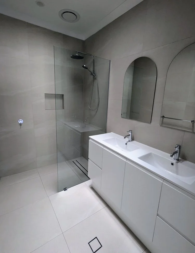 White double vanity with arched mirrors and walk-in shower — ensuite renovation Perth