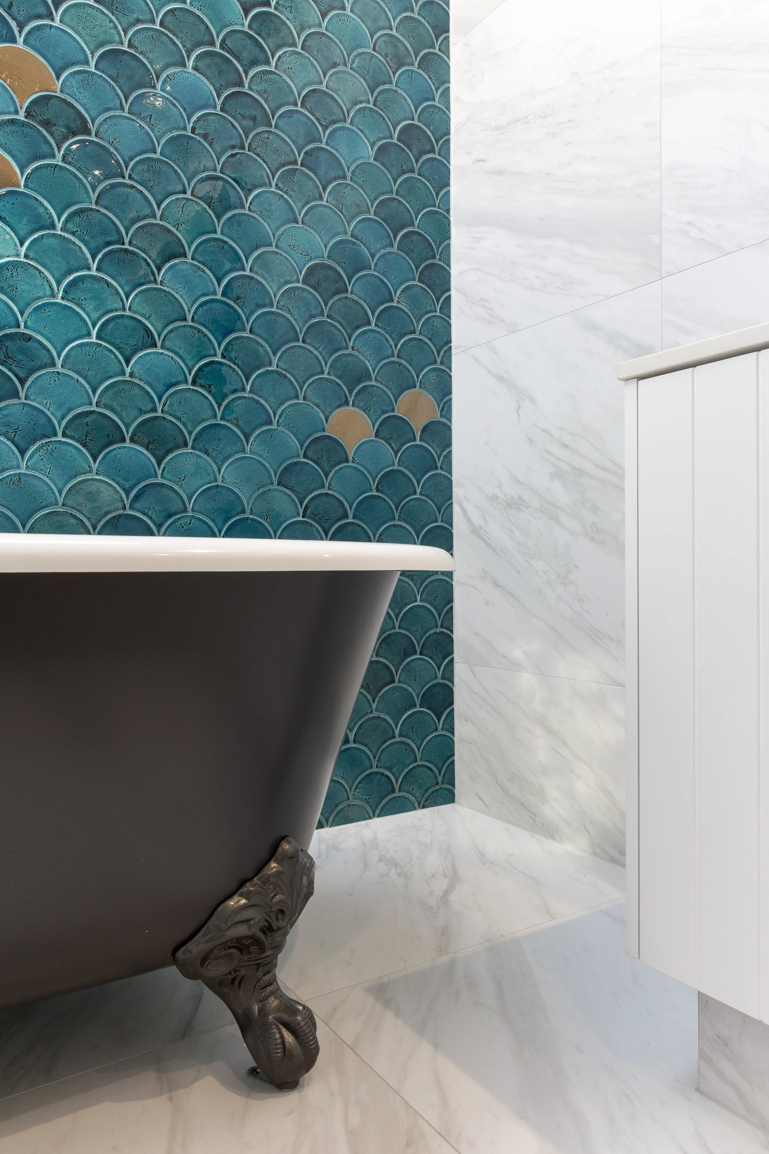 Luxury freestanding clawfoot bath with blue fish scale feature tiles and marble-look walls in a Mount Hawthorn bathroom renovation by Renovation Lane WA.
