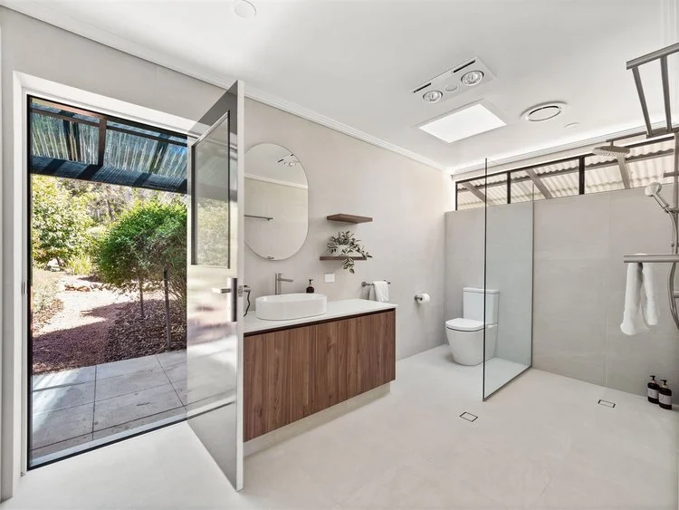 Open plan bathroom with timber vanity, round mirror and large walk-in shower — bathroom renovation Perth