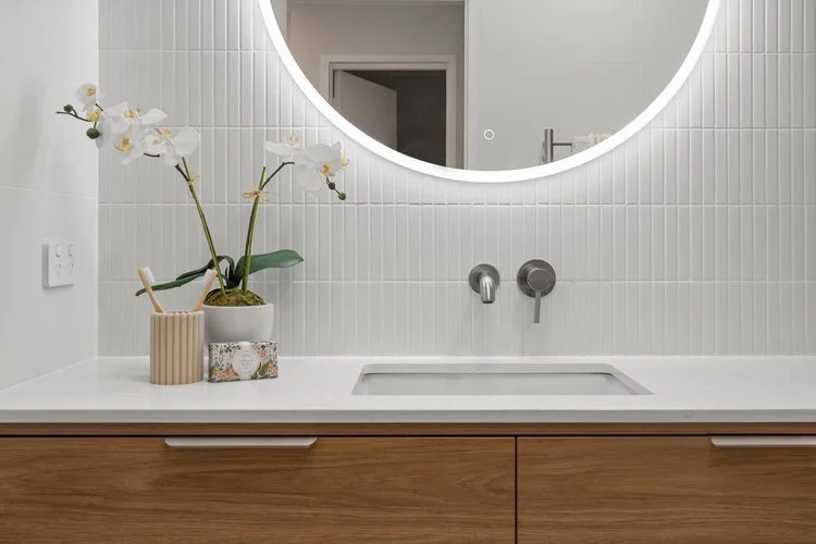 Timber floating vanity with round LED mirror and white stack tiles — bathroom renovation Perth