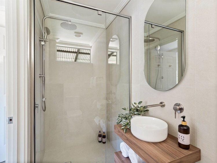 Vessel basin on timber shelf with oval mirror and frameless shower — small ensuite renovation Perth