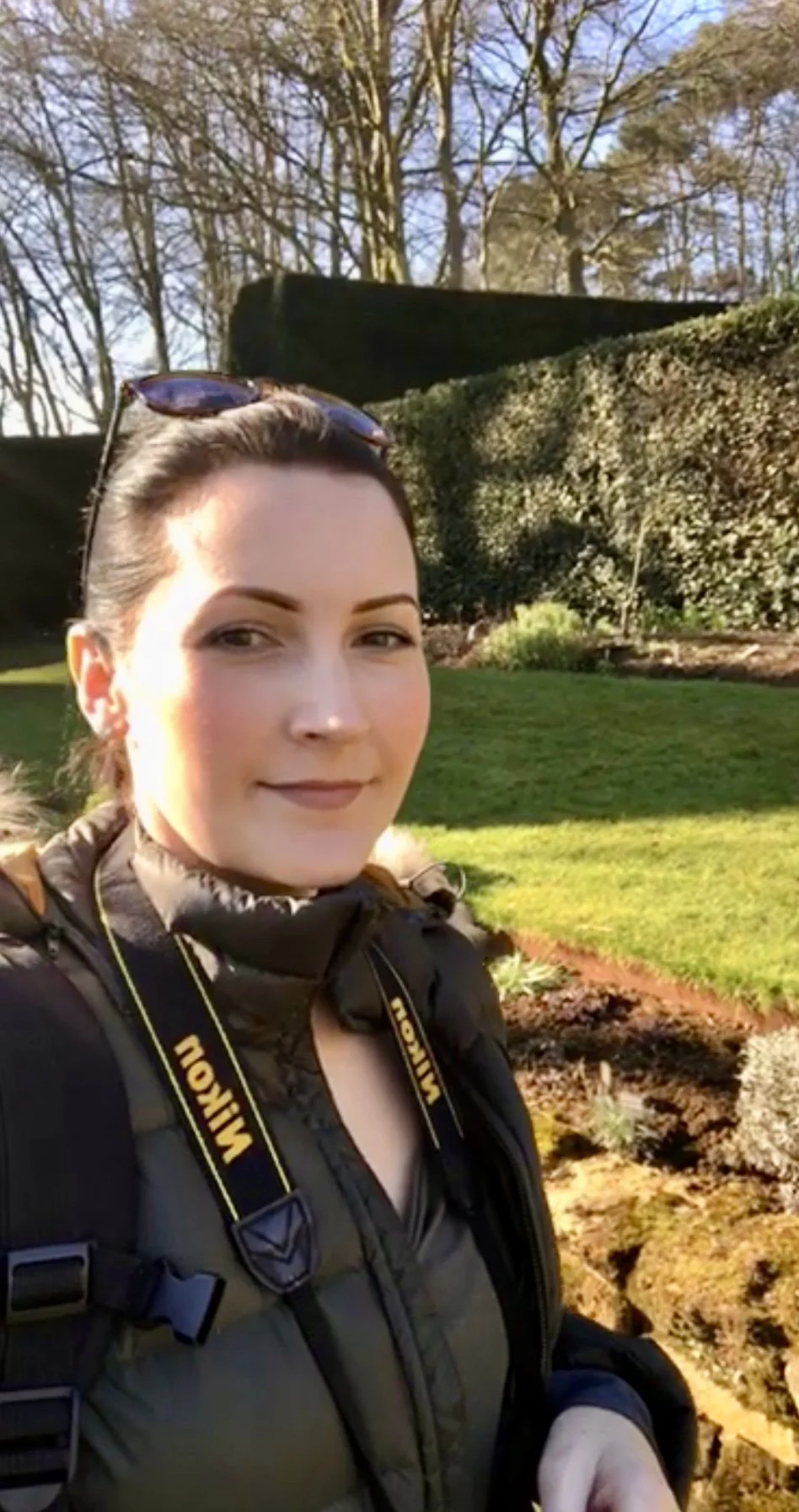 Julia Williams, Photographer and founder of Antler & Rose, standing outdoors with her Nikon camera.