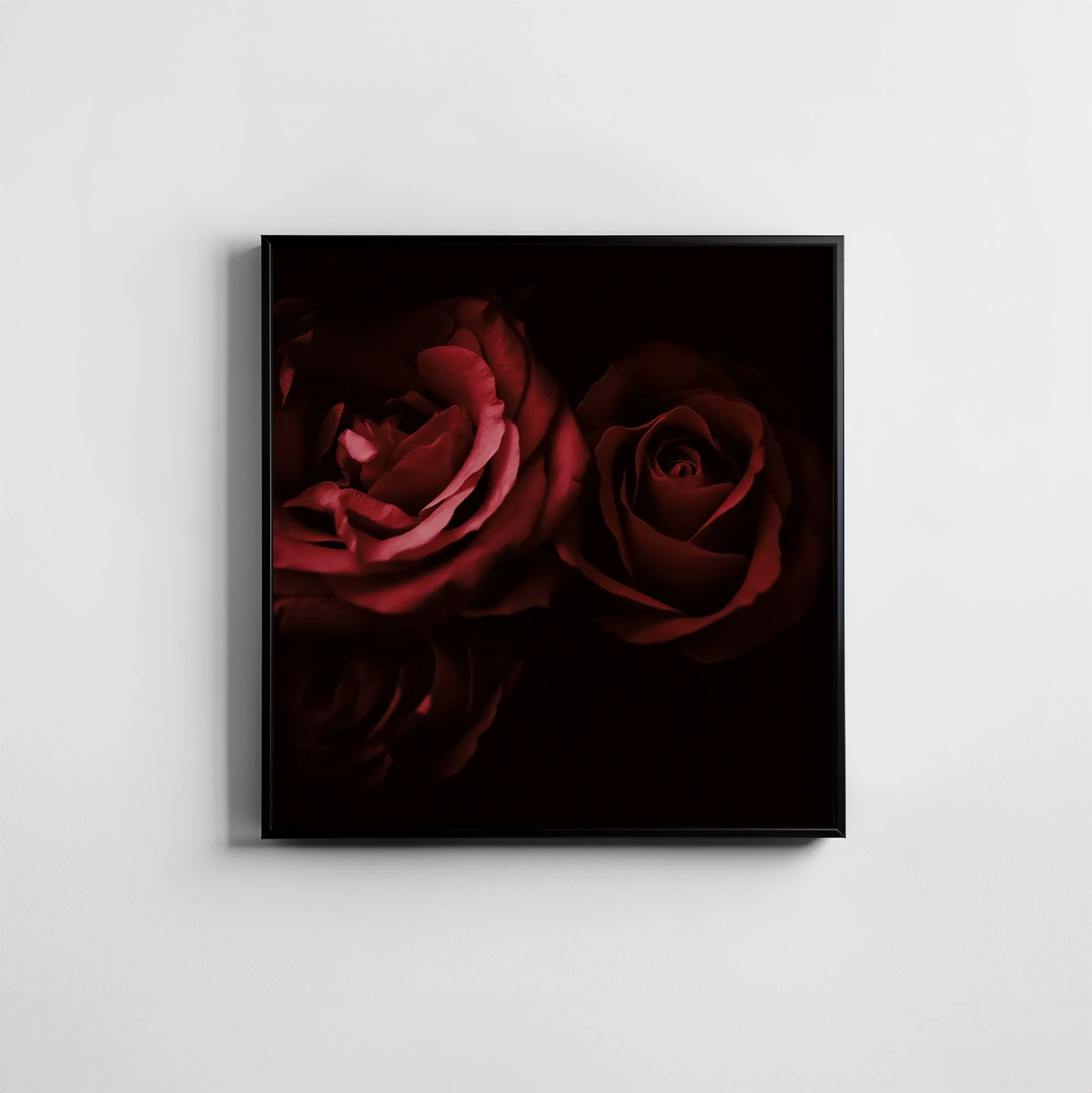 Greeting card with deep red roses on a dark background, displayed in a thin black frame on a wall.