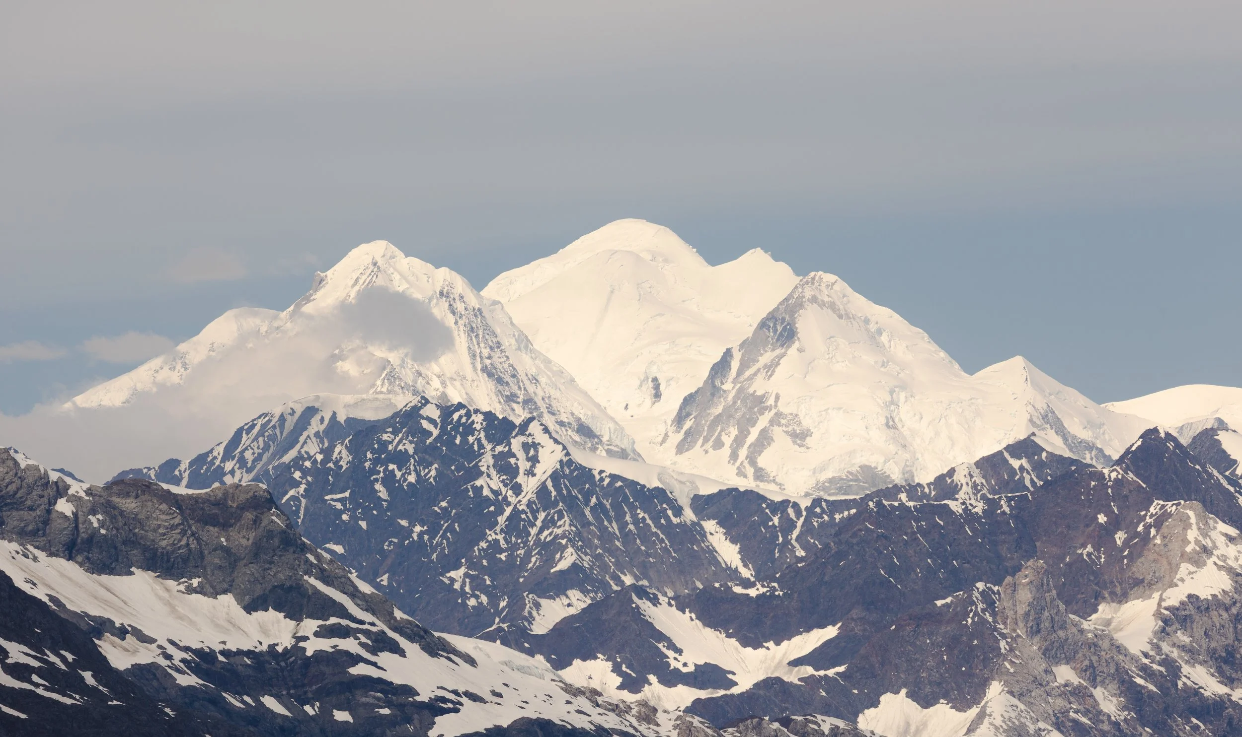 Snow-covered mountain peaks against a cloudy sky.