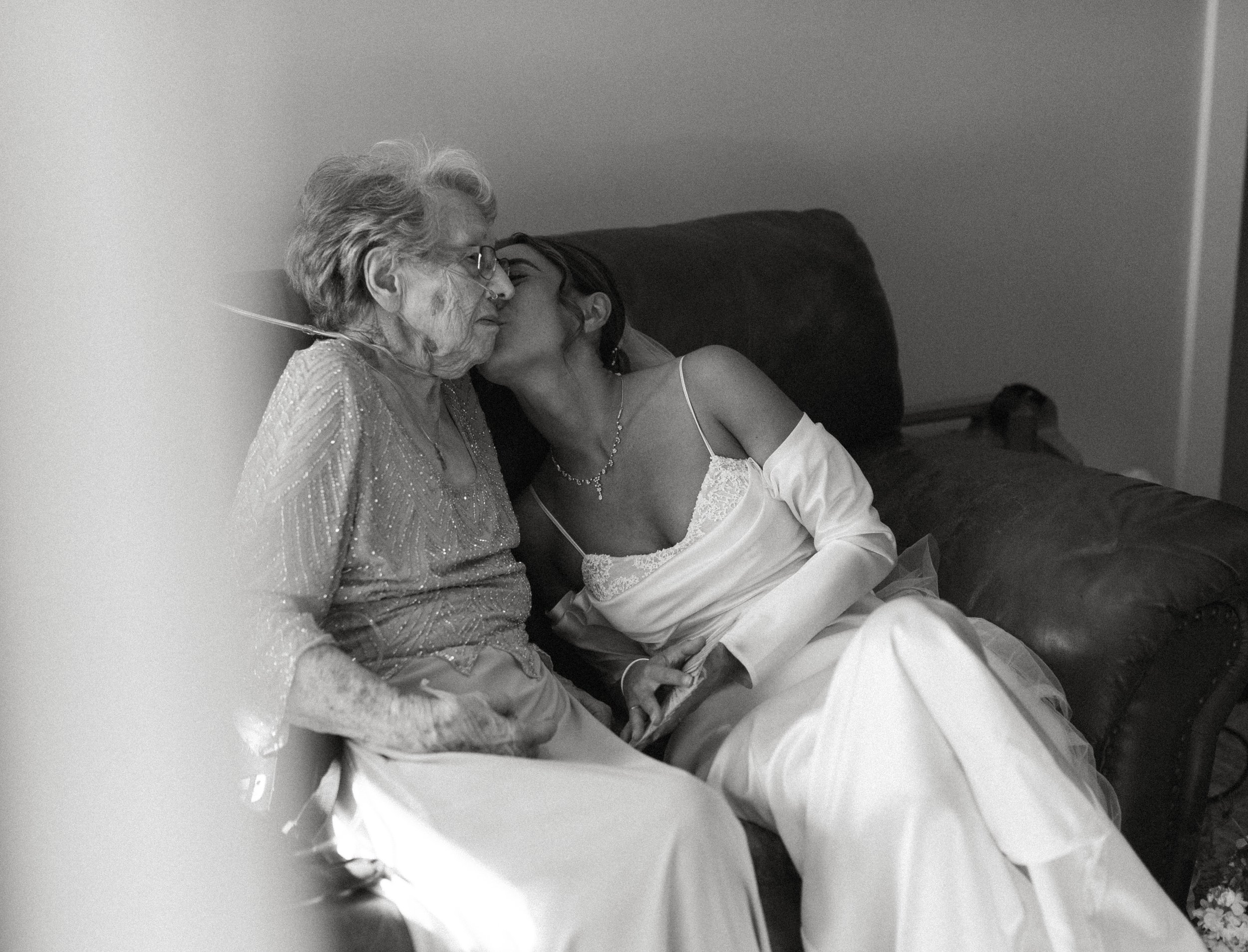 Emotional black and white photo of bride kissing elderly family member before wedding ceremony