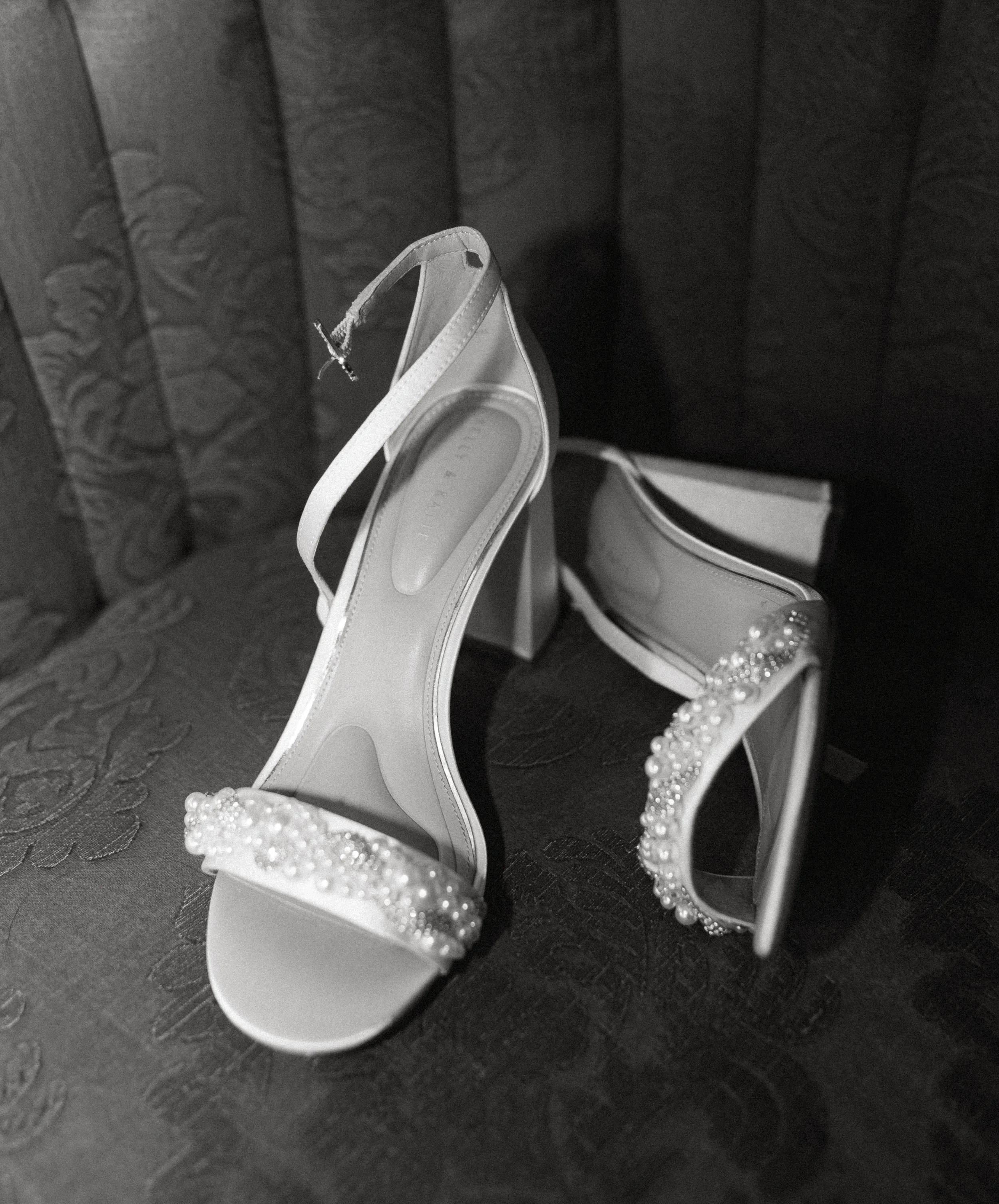 Wedding detail flat lay with bridal shoes, rings, and invitation suite