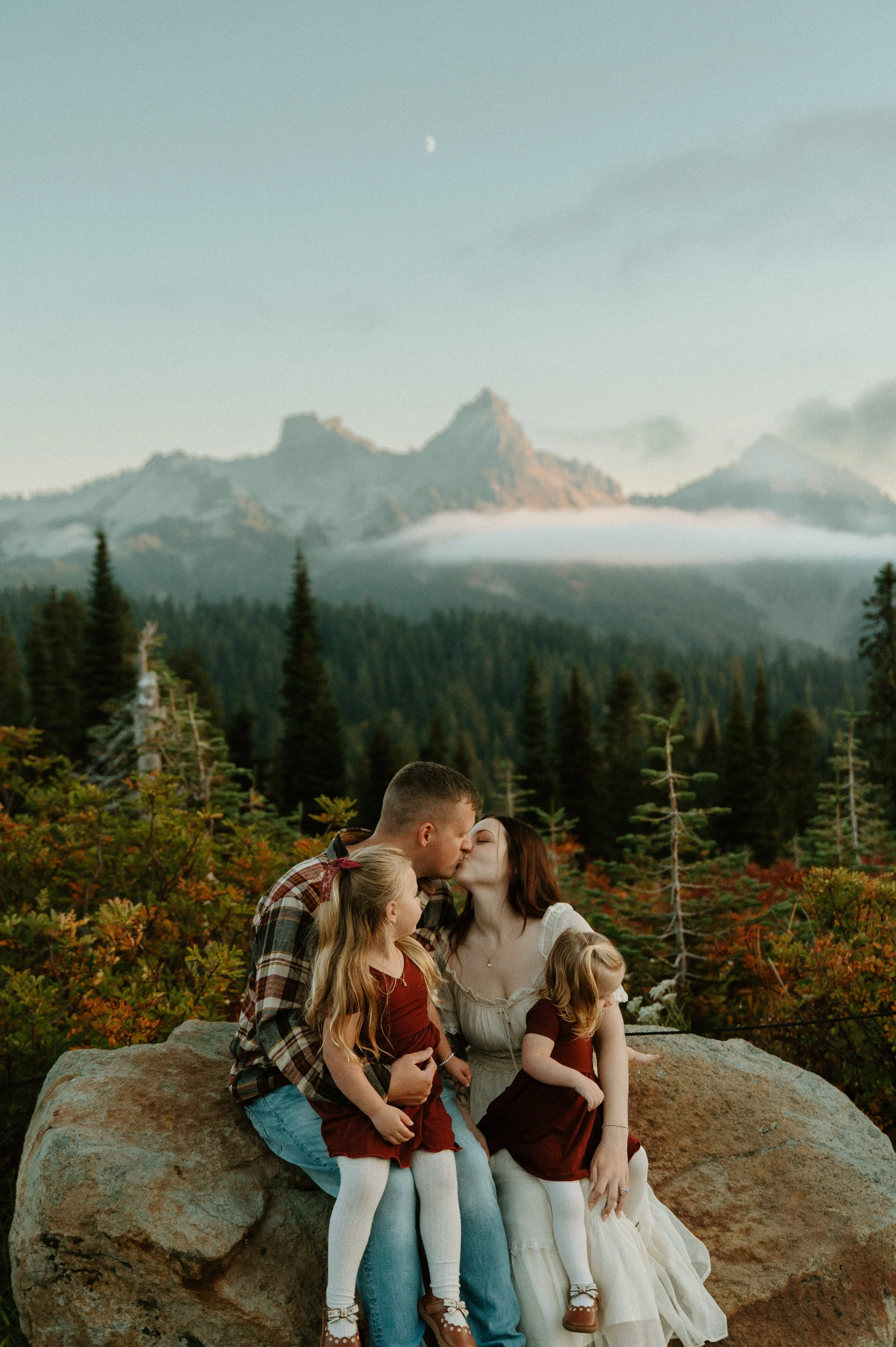     Family of four sitting together with mountain views and colorful fall foliage at Mount Rainier.