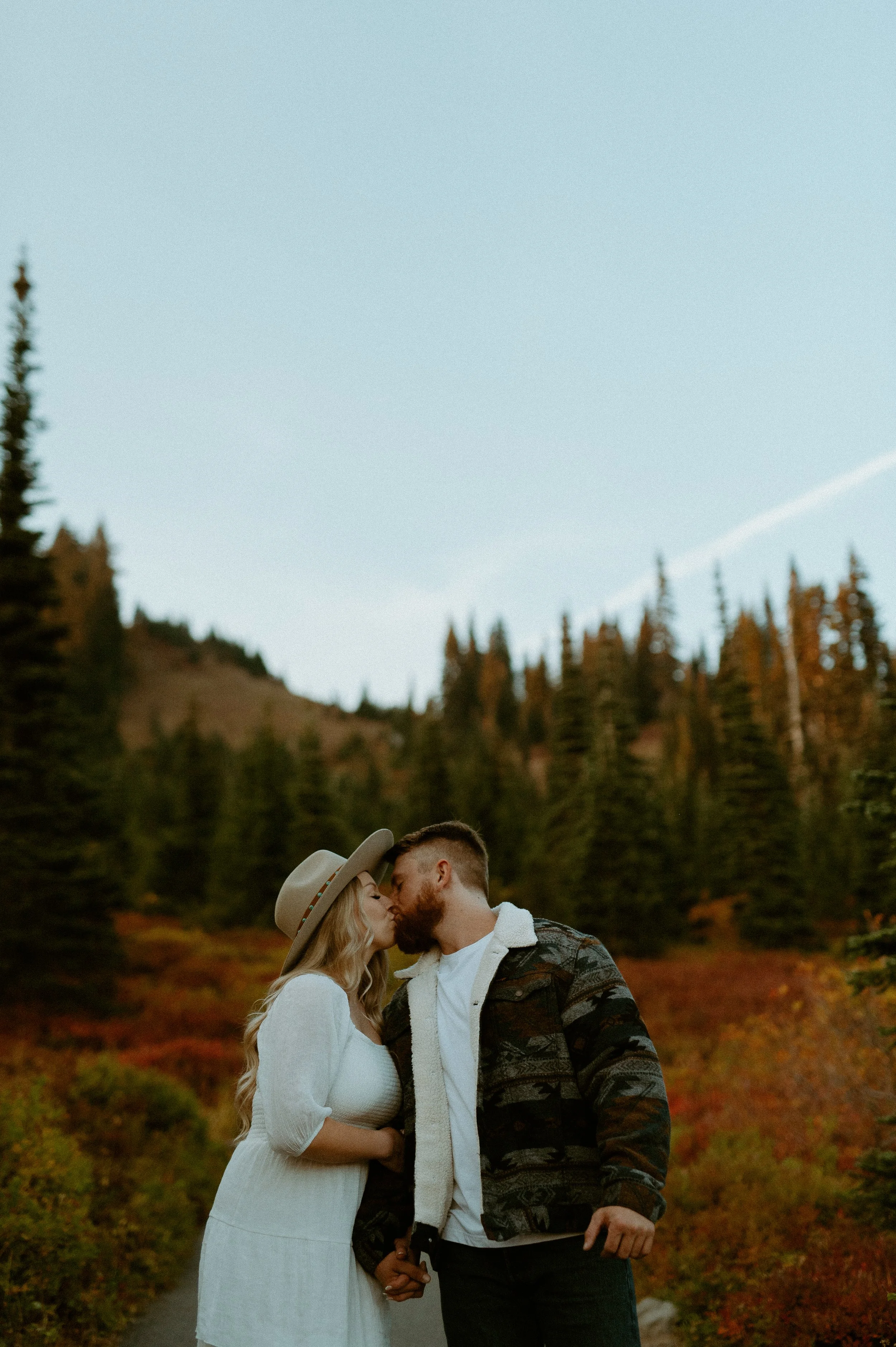 Couple kissing on a forest trail during a fall engagement session at Mount Rainier National Park