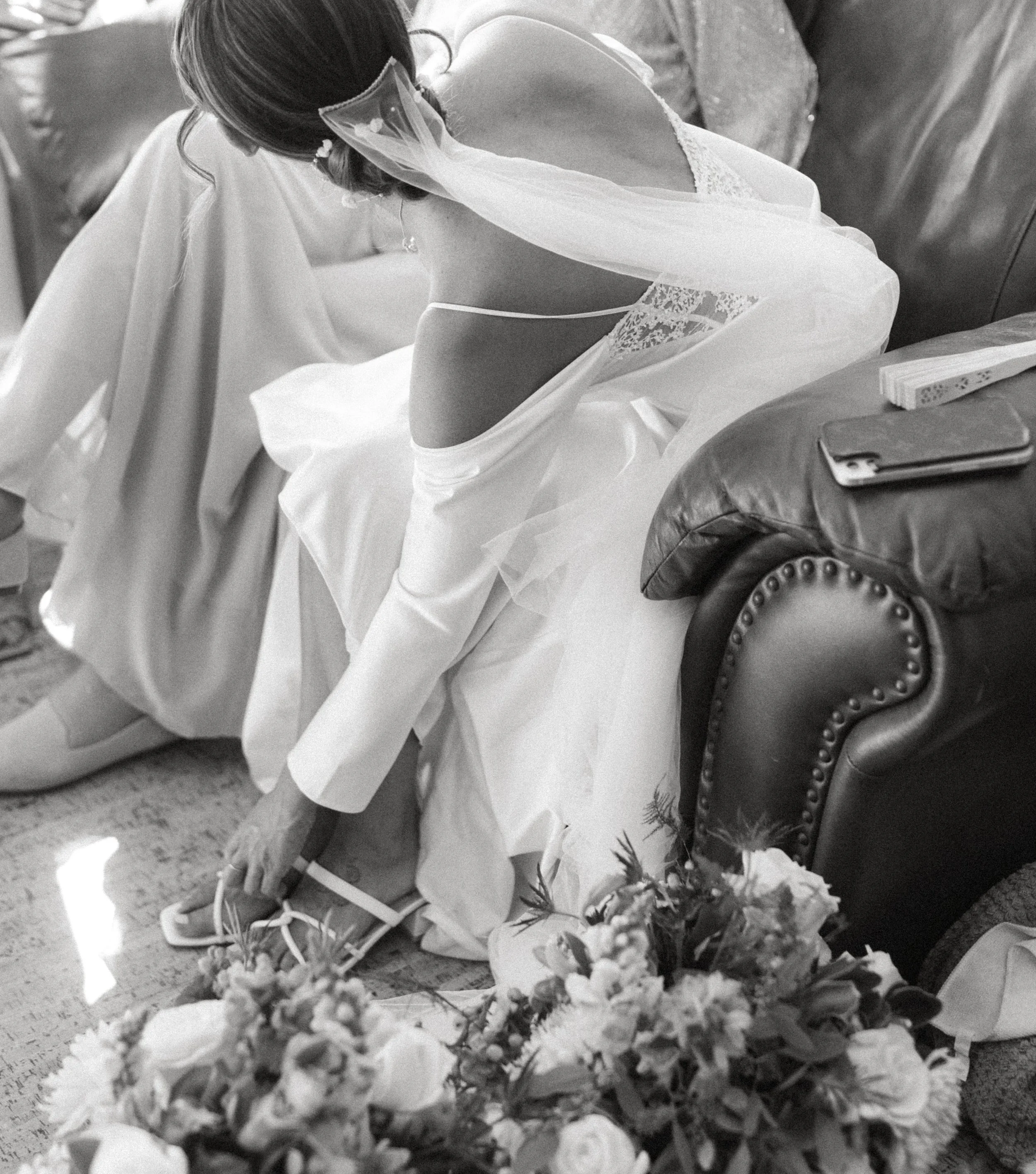 Black and white photo of bride sitting on floor getting ready before backyard wedding in Seattle