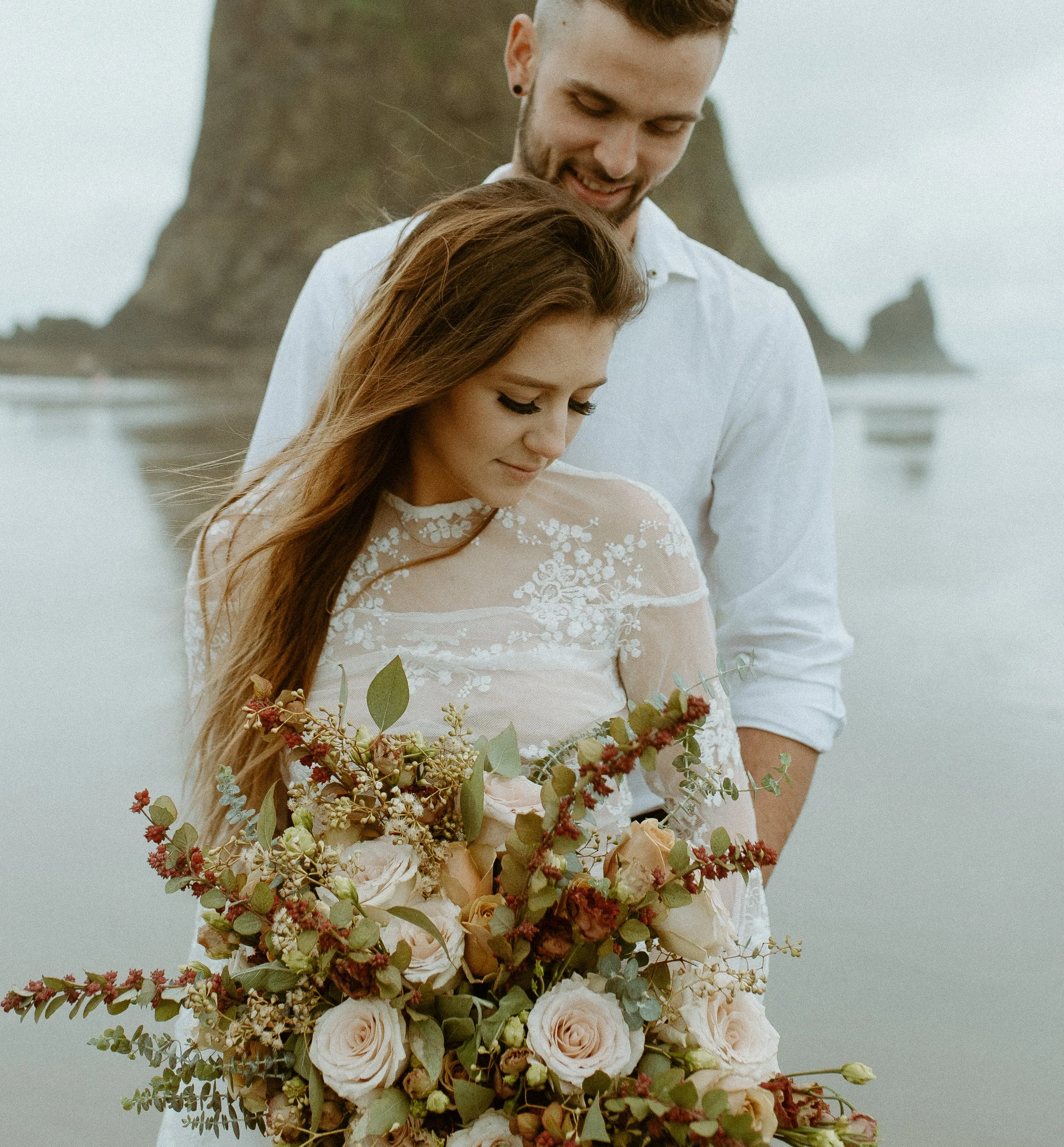 Romantic portrait of bride and groom in front of Haystack Rock during a cloudy Cannon Beach elopement session