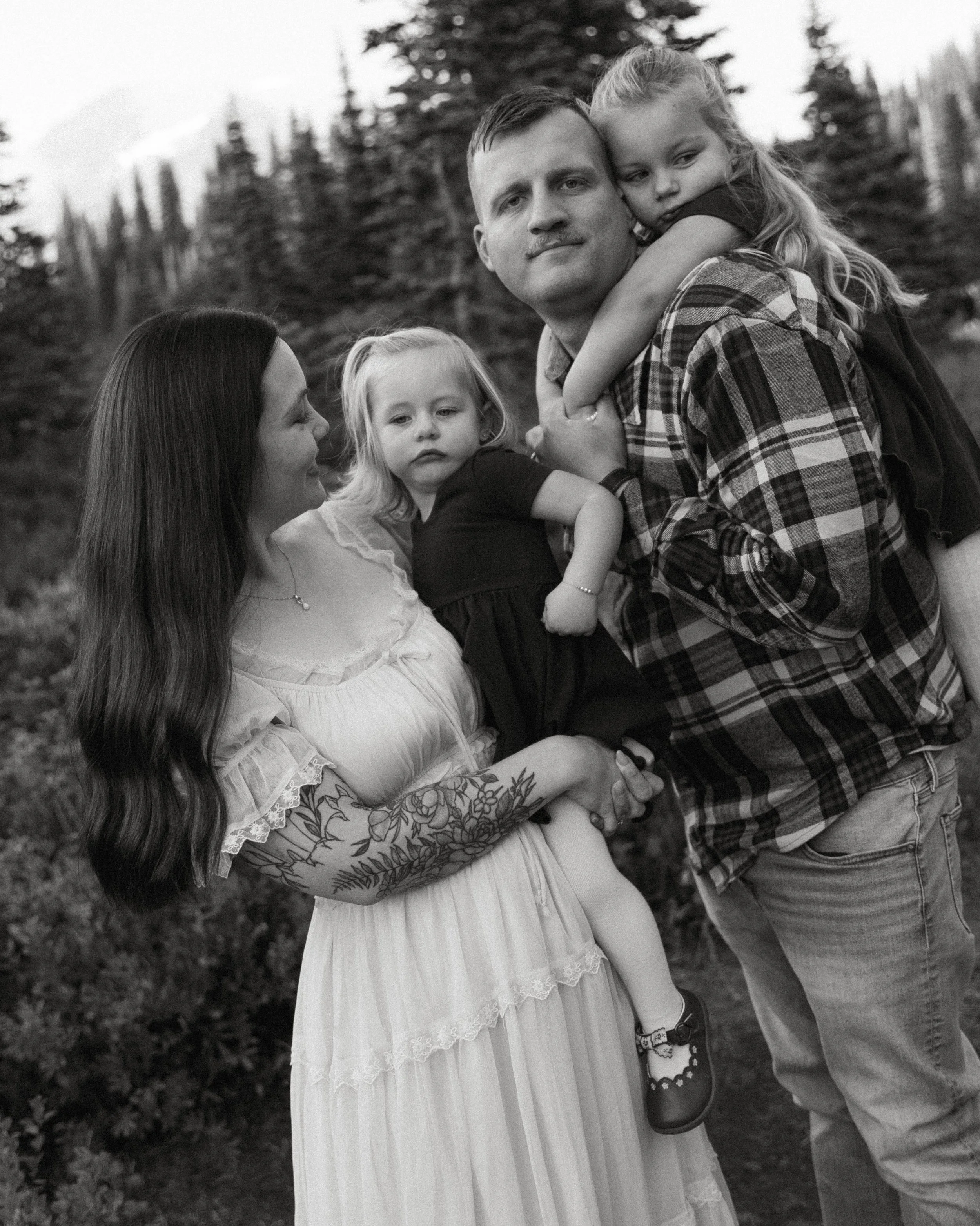     .    Black and white candid portrait of parents holding their two daughters during a Mount Rainier family session
