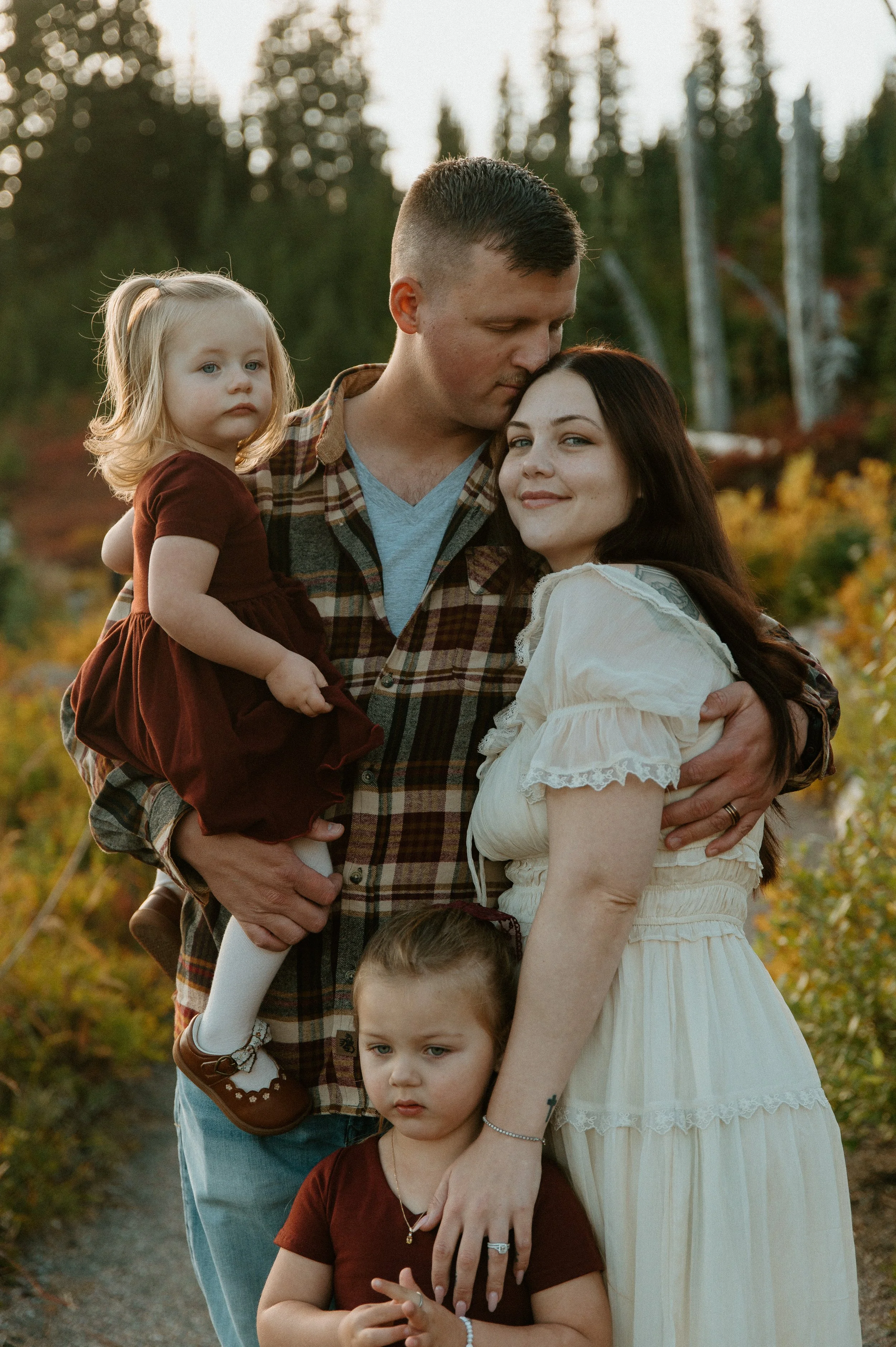     Family of four embracing in golden evening light during fall family photos at Mount Rainier National Park.